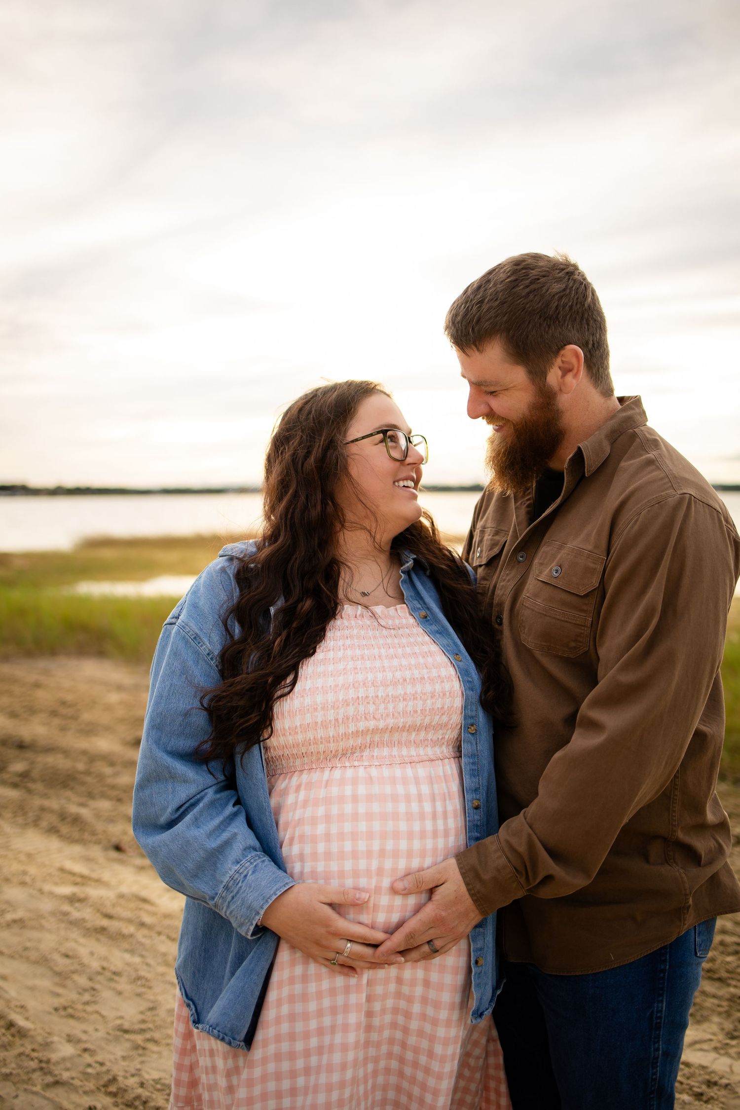 Intimate maternity photo of couple embracing on beach at sunset.