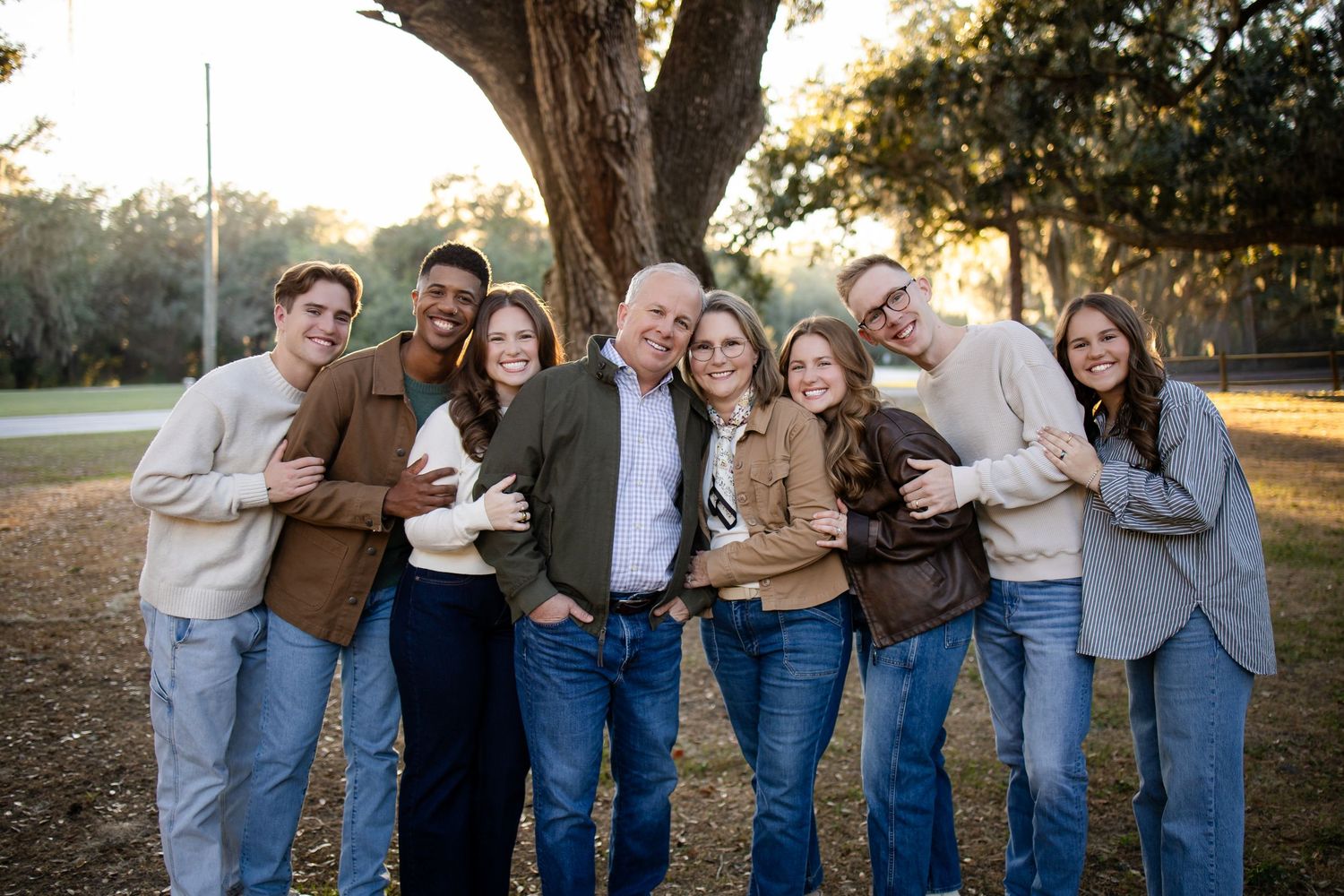 Group photo of friends in matching denim and neutral colors leaning against each other outdoors.