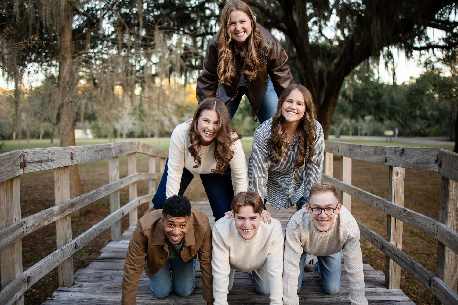 A group enjoying a fun photo session on a wooden bridge surrounded by trees.