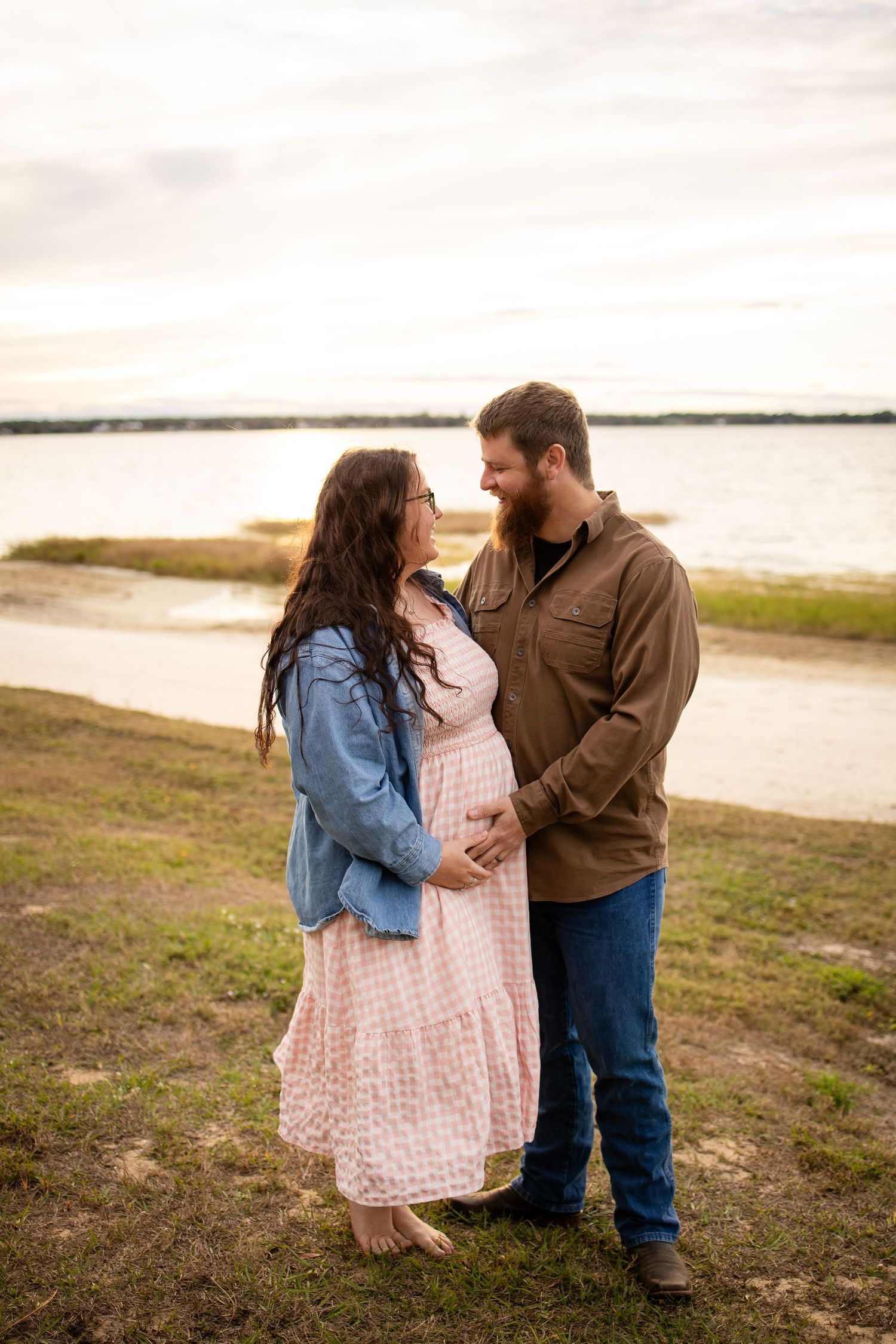 Couple in denim and casual wear sharing affectionate moments by the water.
