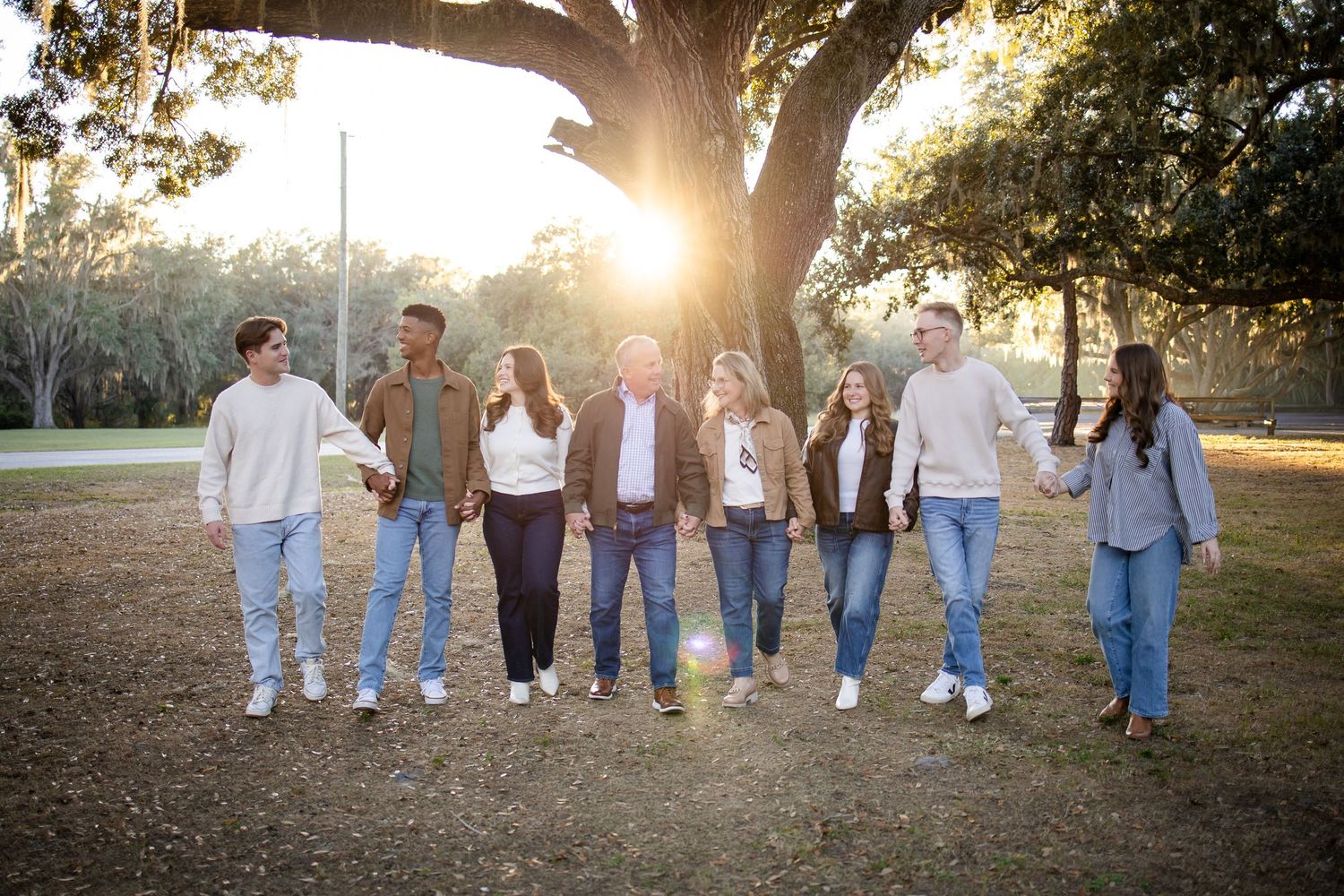 Group photo showing people walking in line under tree branches at golden hour.
