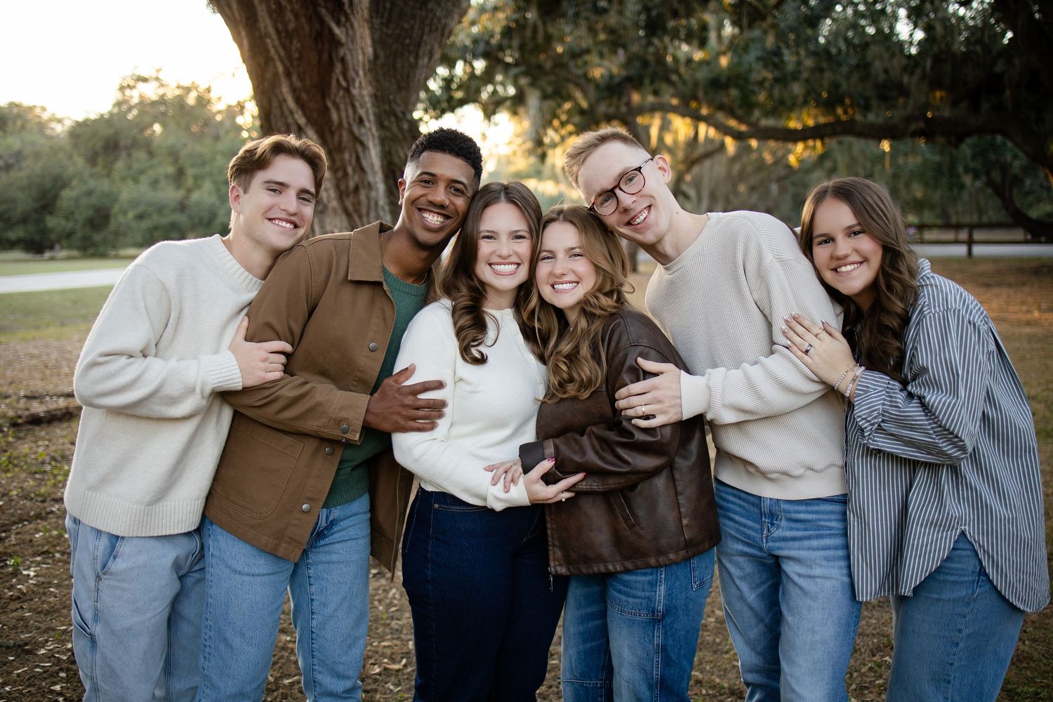 Friends laughing together in matching casual outfits during an outdoor photo session.