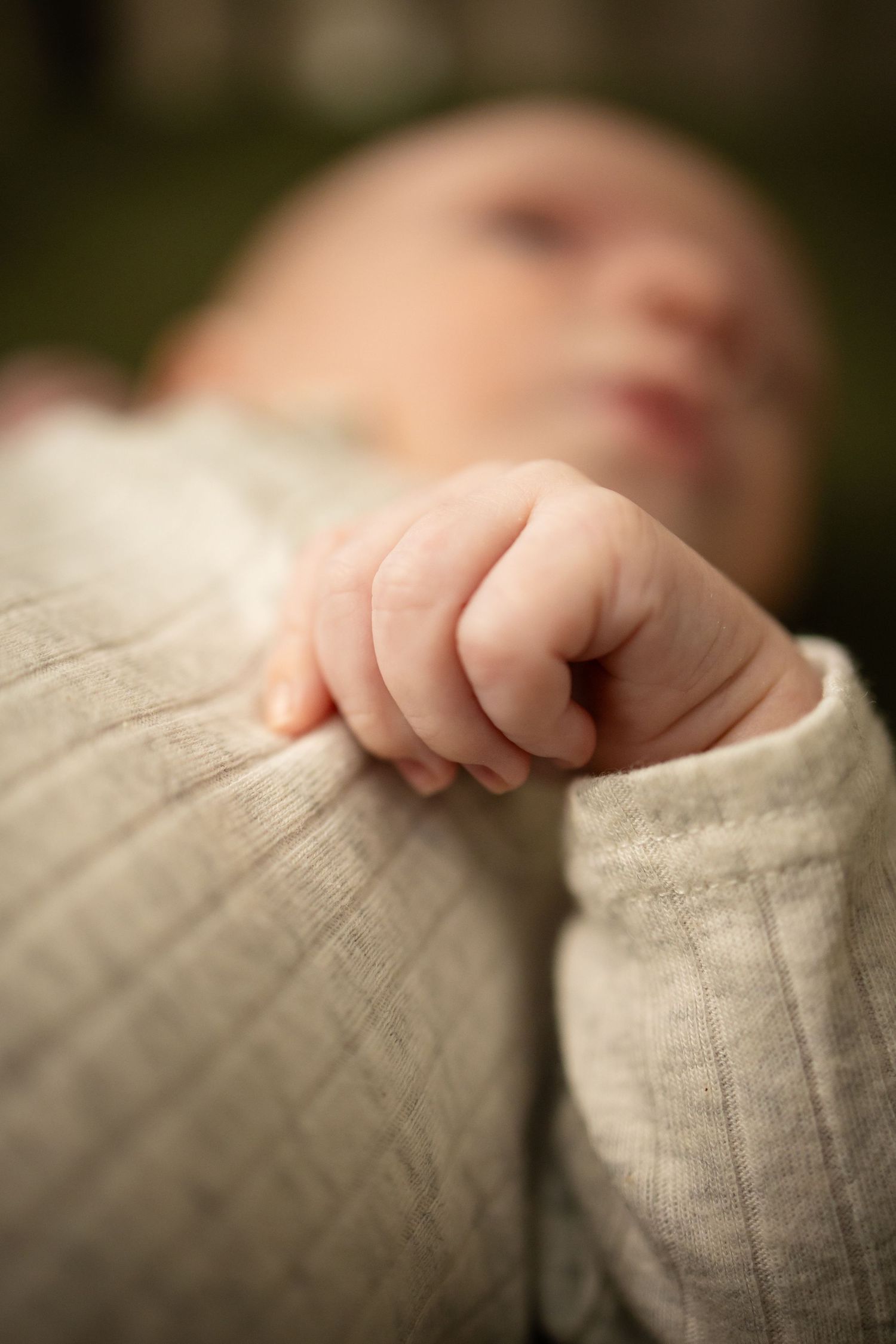 Close-up image sequence showing tiny fingers grasping gray knit fabric in soft natural lighting.