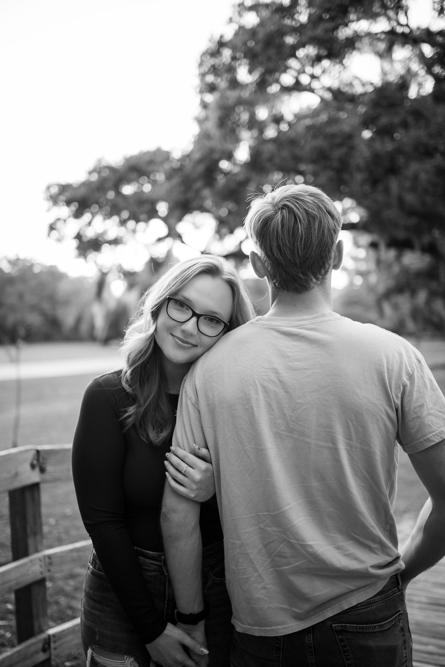 A couple shares an intimate moment together on a wooden bridge in black and white photography.