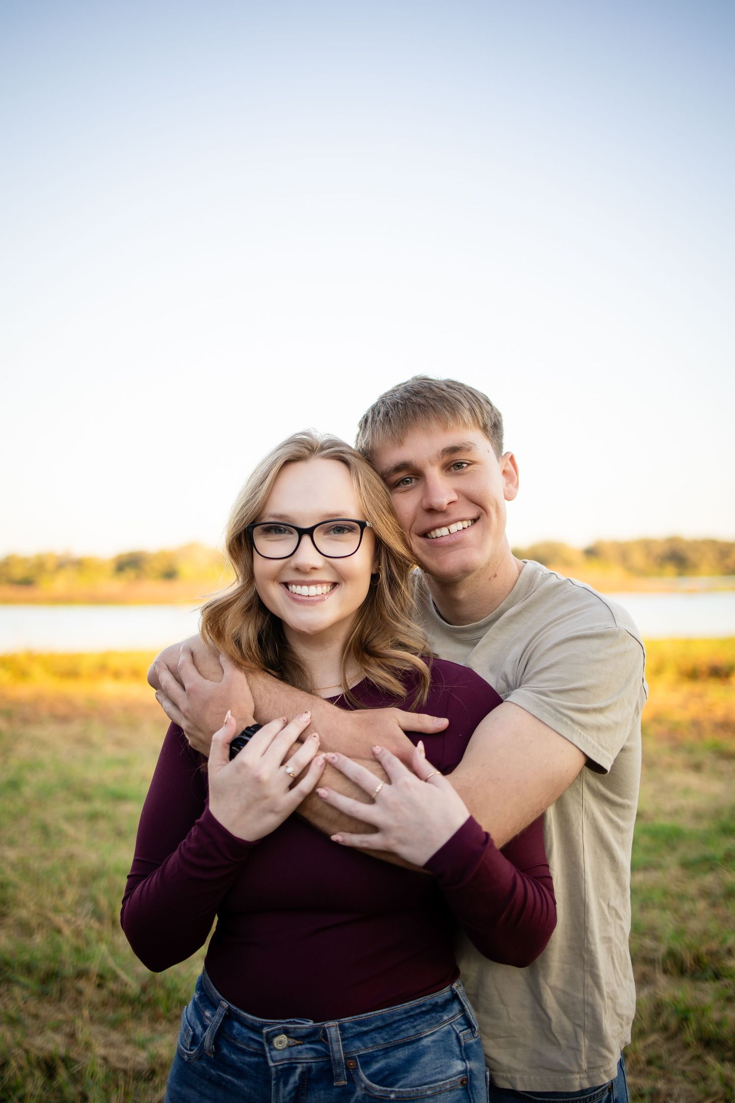 A couple shares a tender moment in a sunny field during golden hour.