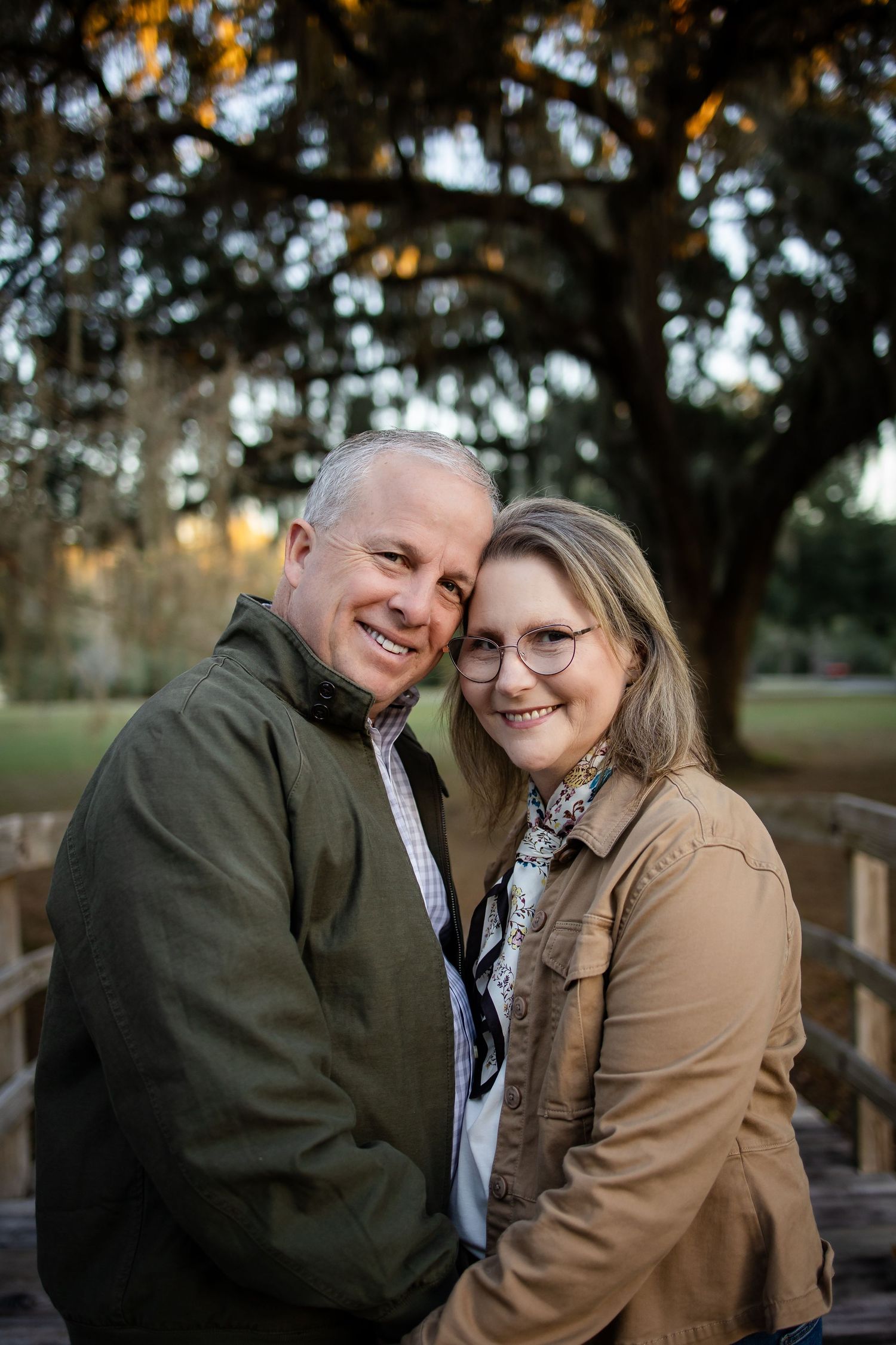 A couple shares an intimate moment on a wooden bridge during golden hour.