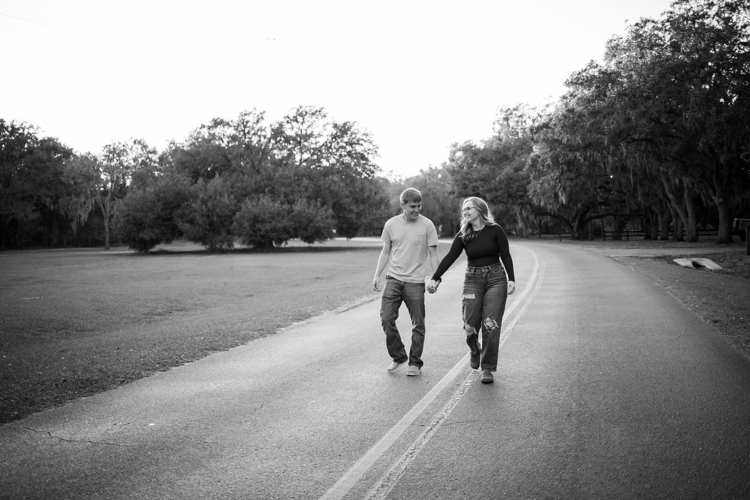 A black and white landscape photo of people walking along a tree-lined path.