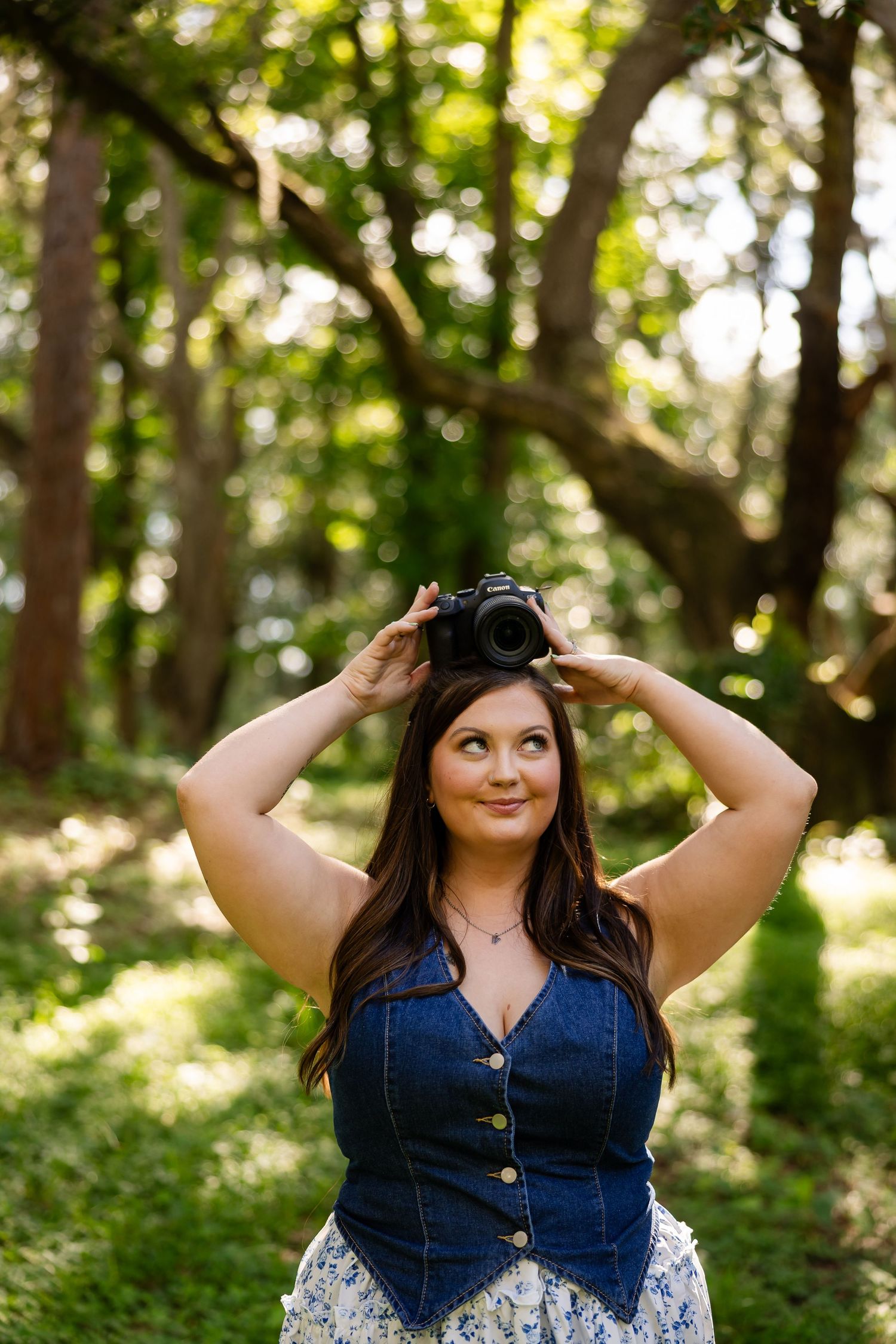Portrait session in a sunlit forest wearing denim and creating dynamic poses with natural bokeh effect.