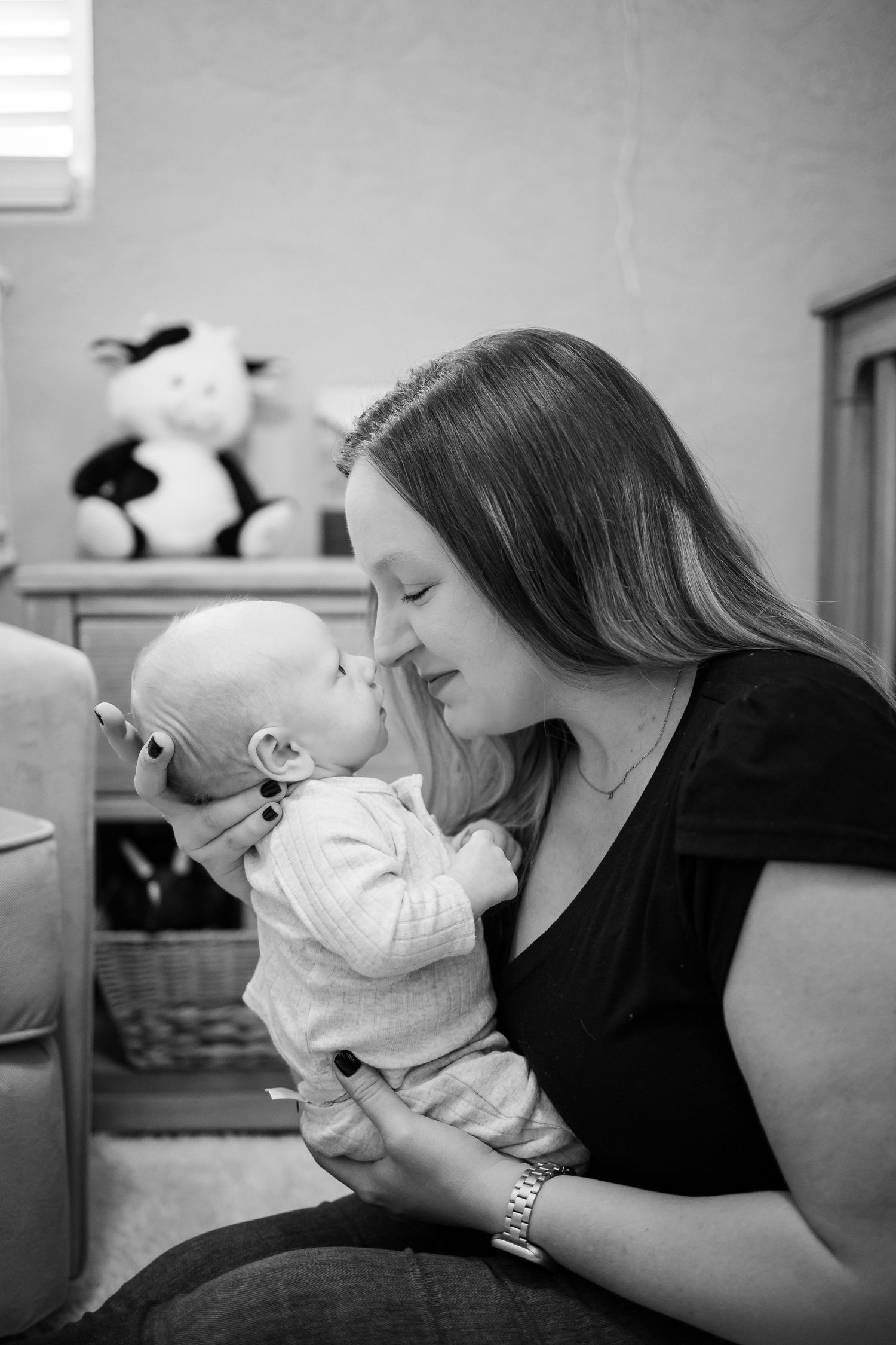A tender black and white moment shows mother and baby nuzzling together in an intimate embrace at home.