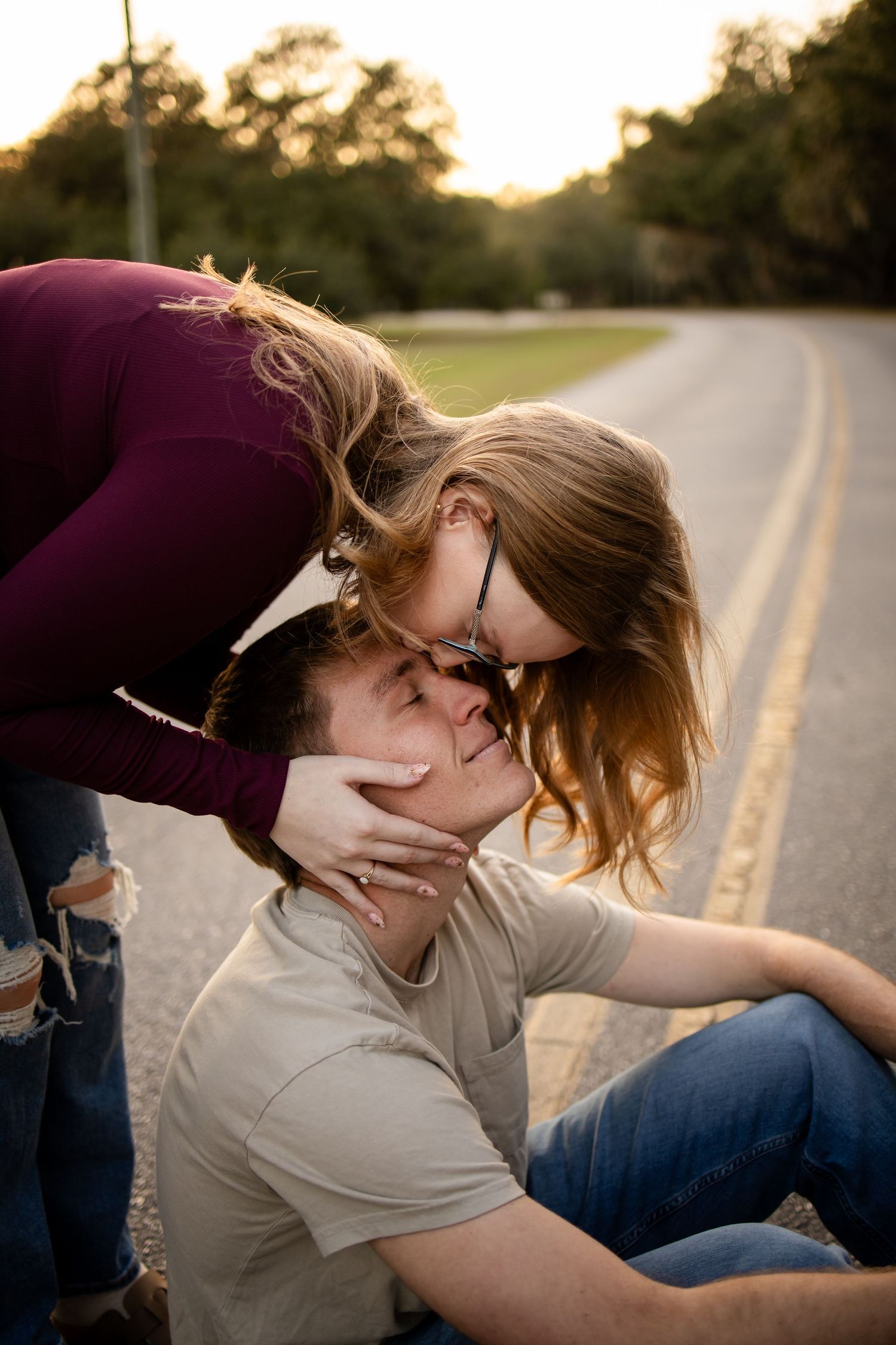 A playful couple shares a tender moment on a sunset-lit road.