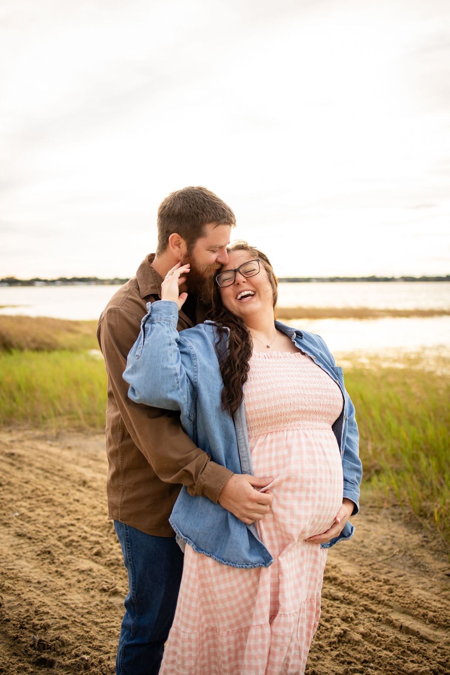 Joyful couple laughing together during outdoor photoshoot near water.