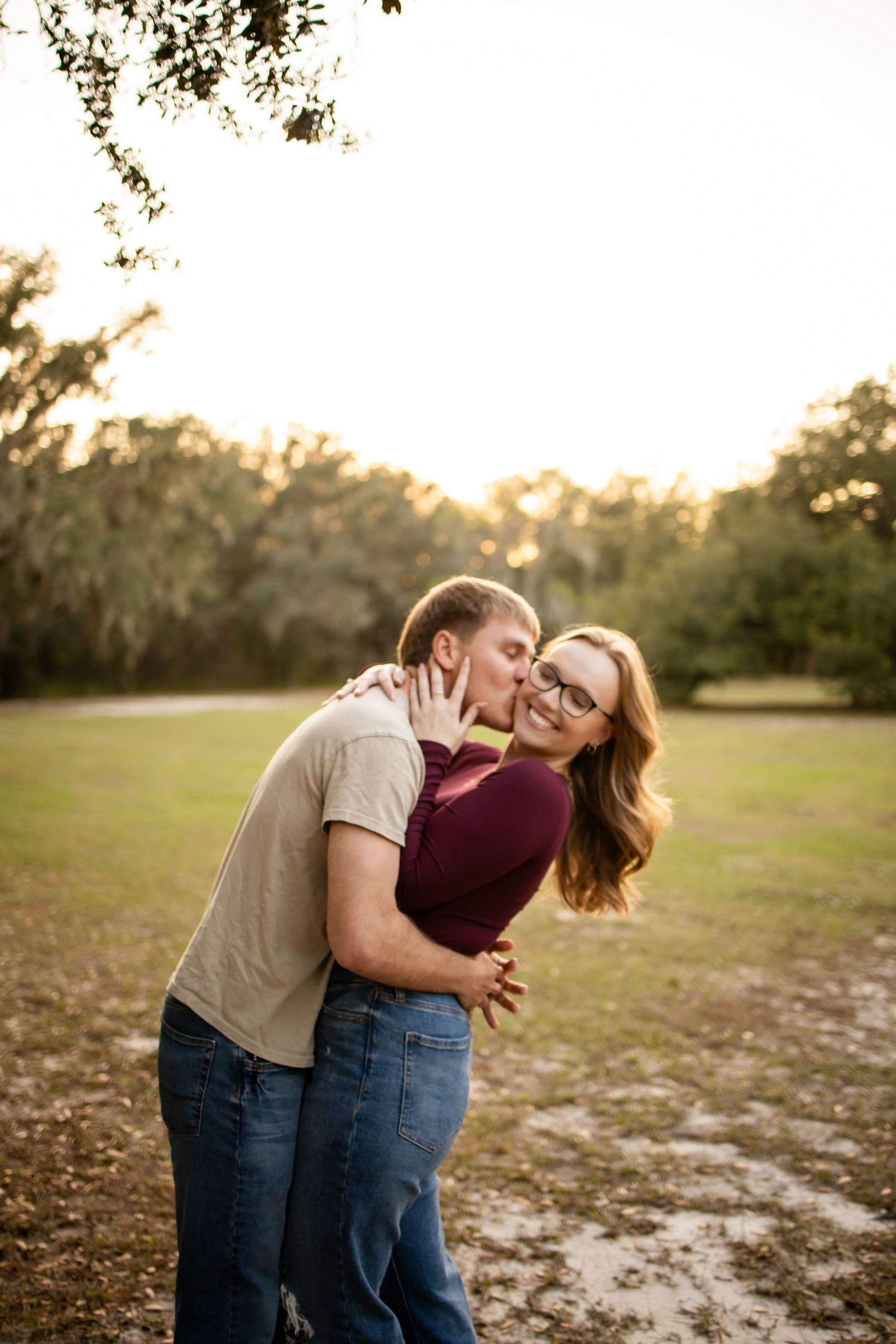A couple shares a romantic embrace in a field during golden hour.