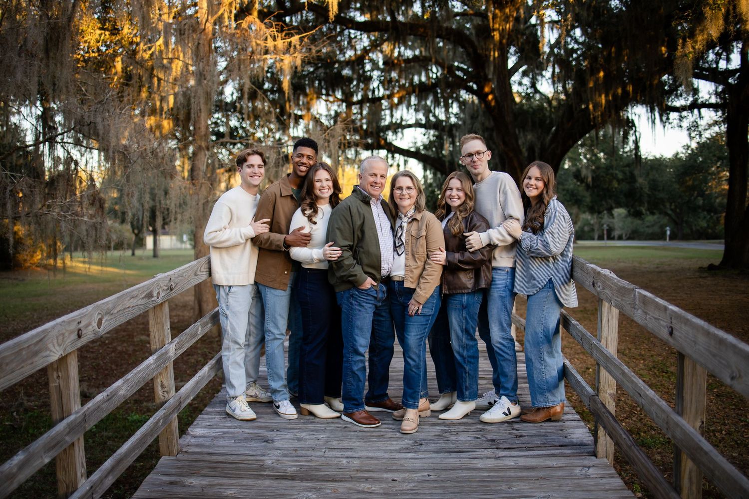 Family photo session on a wooden bridge surrounded by Spanish moss draped trees.