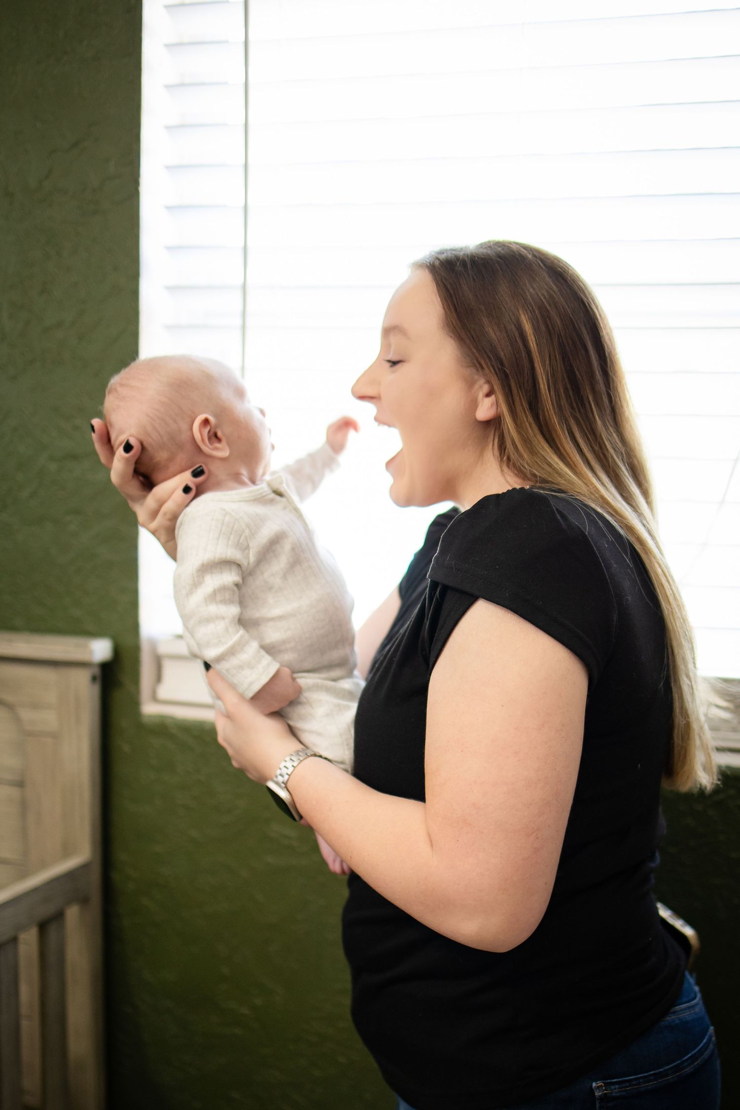 A sequence of photos shows a caregiver in a black shirt tenderly lifting and holding a baby in white clothing.