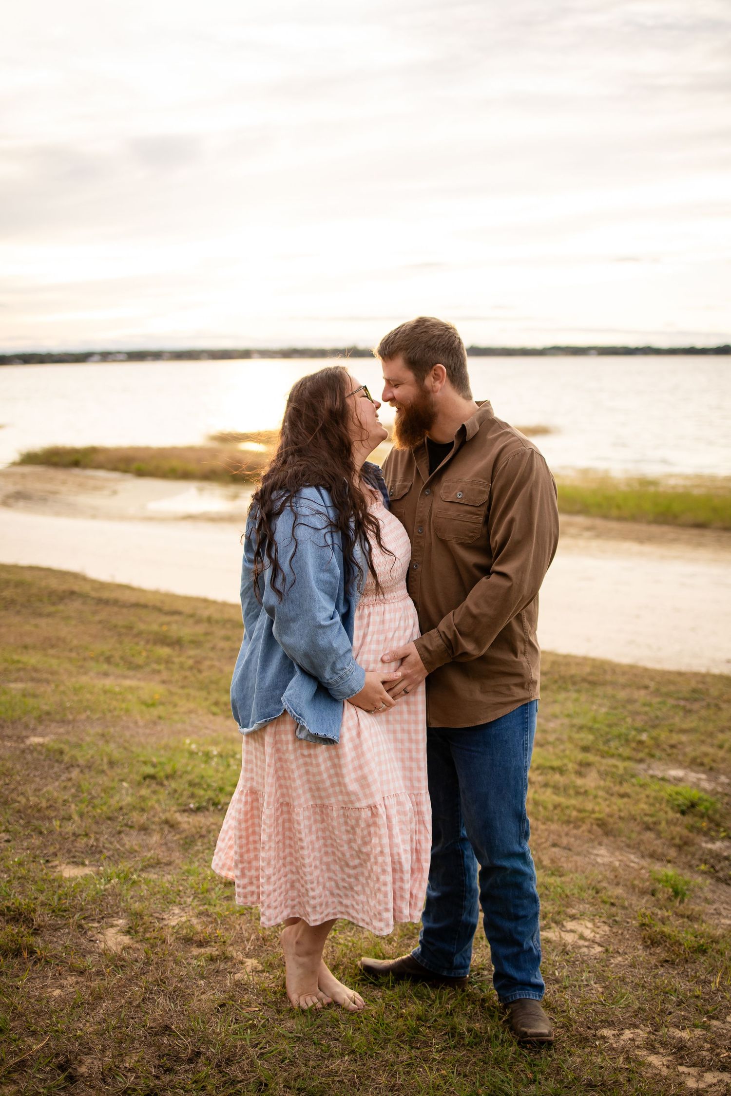 Romantic couple embracing on shoreline during golden hour sunset.