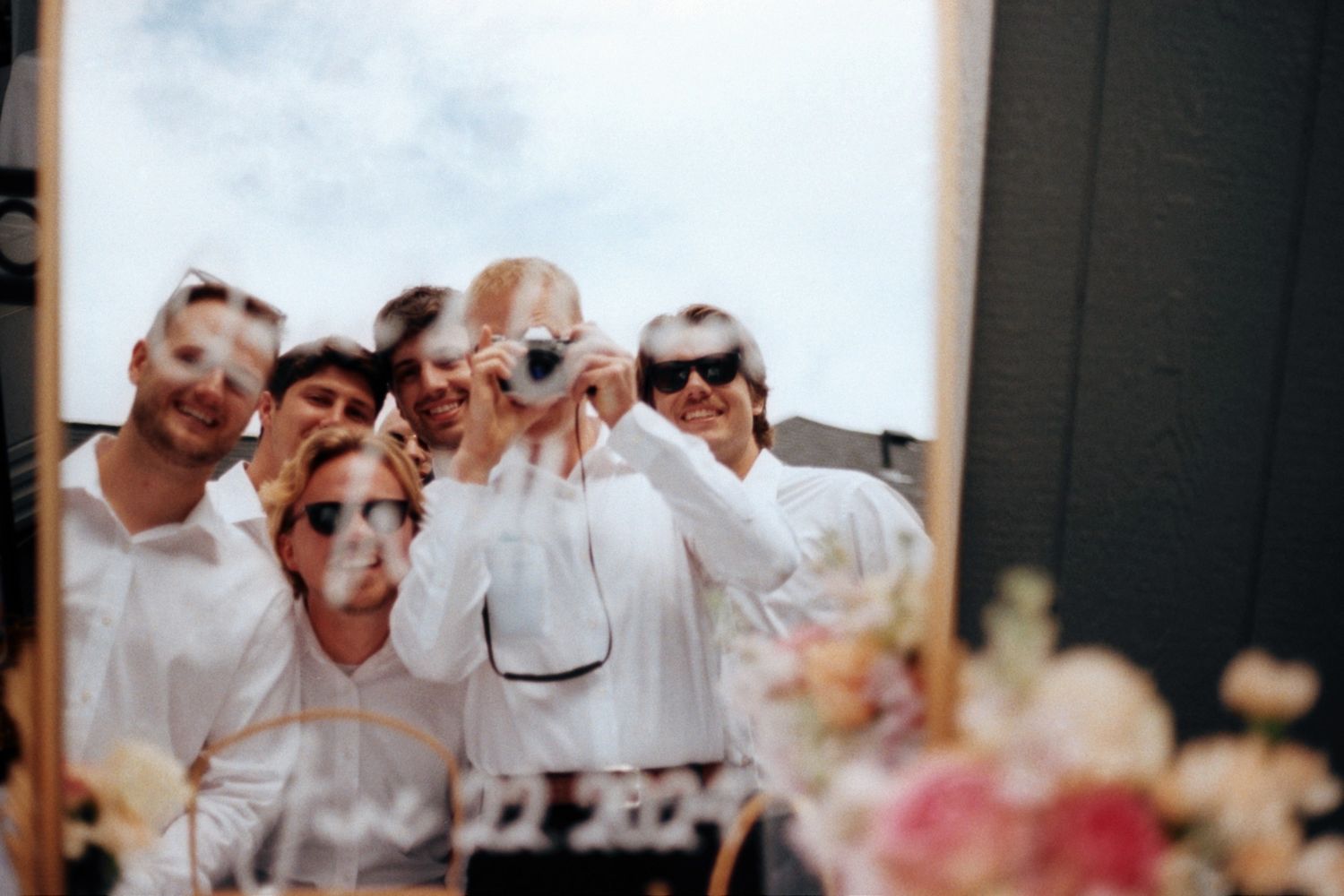 Wedding guests dance and celebrate on a crowded dance floor at an indoor reception venue.