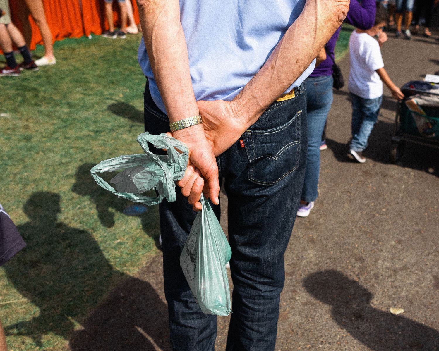 Person holding a reusable shopping bag at an outdoor market or event.
