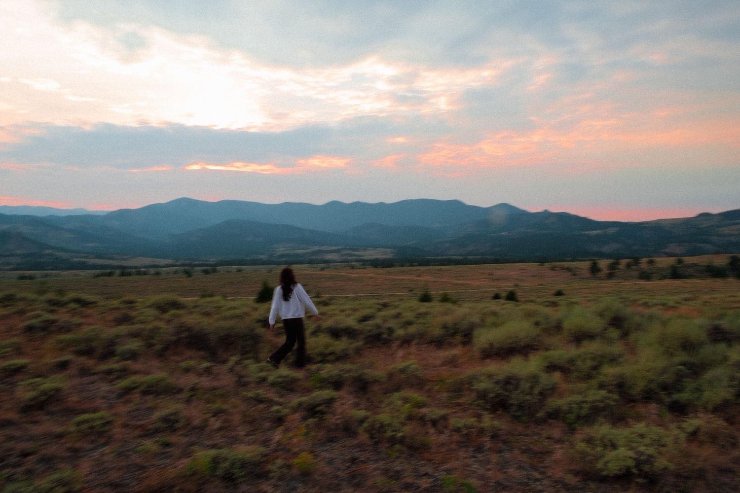 Panoramic desert landscape at sunset with mountains in the distance.