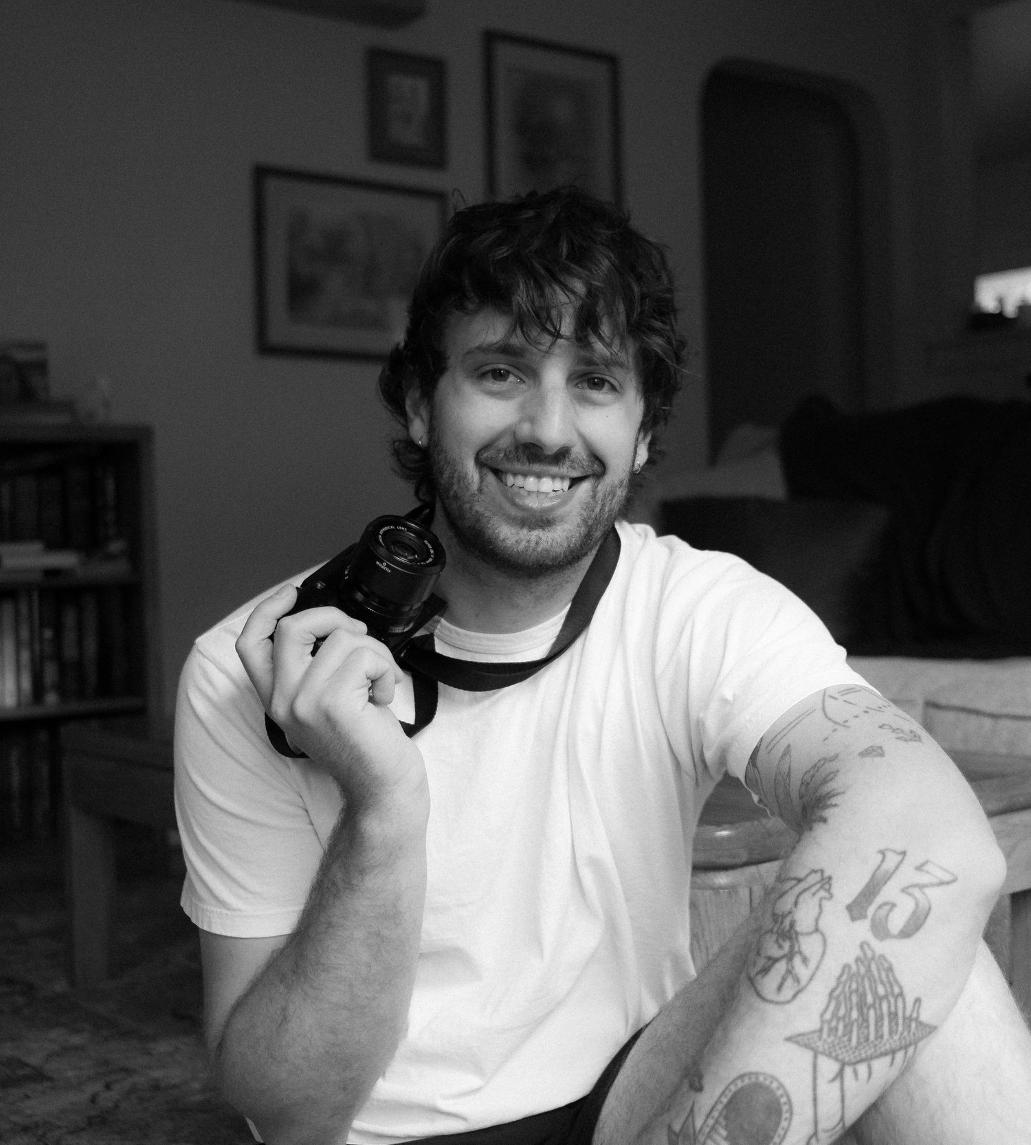 A casual portrait of someone in a white t-shirt holding a small black cat indoors.