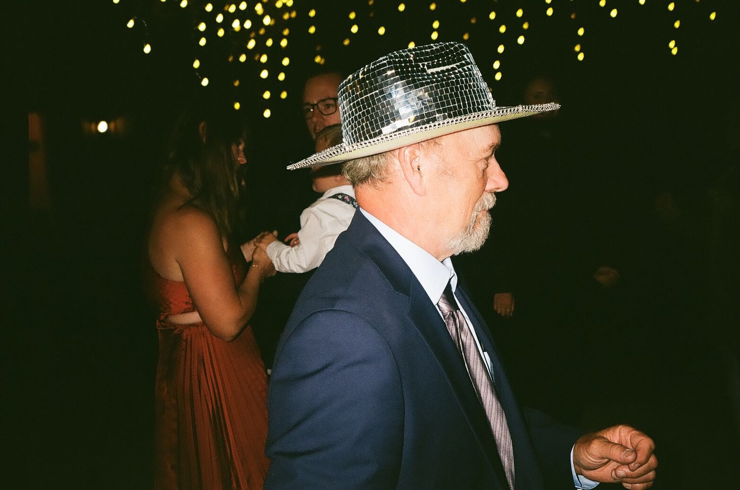 Party scene with someone wearing a sparkly hat under twinkling lights.