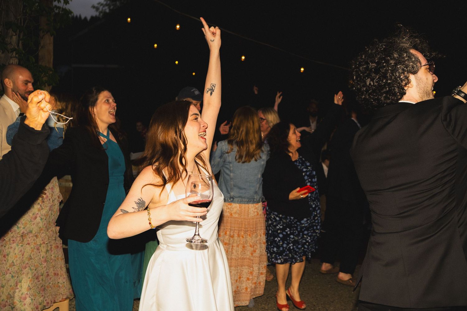 Wedding reception guests dancing and celebrating on a dark dance floor.