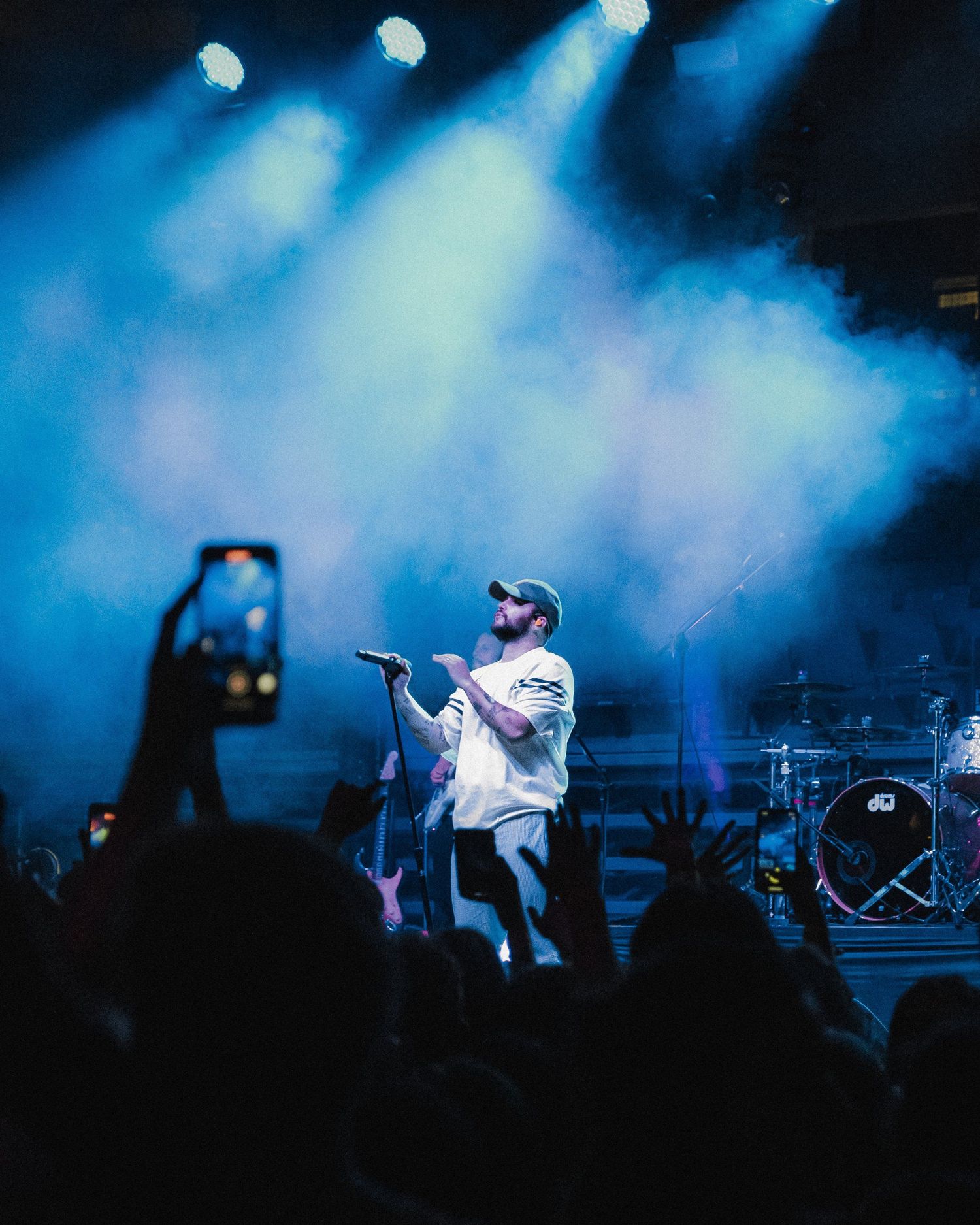 Concert performance with dramatic blue stage lighting and fog effects.