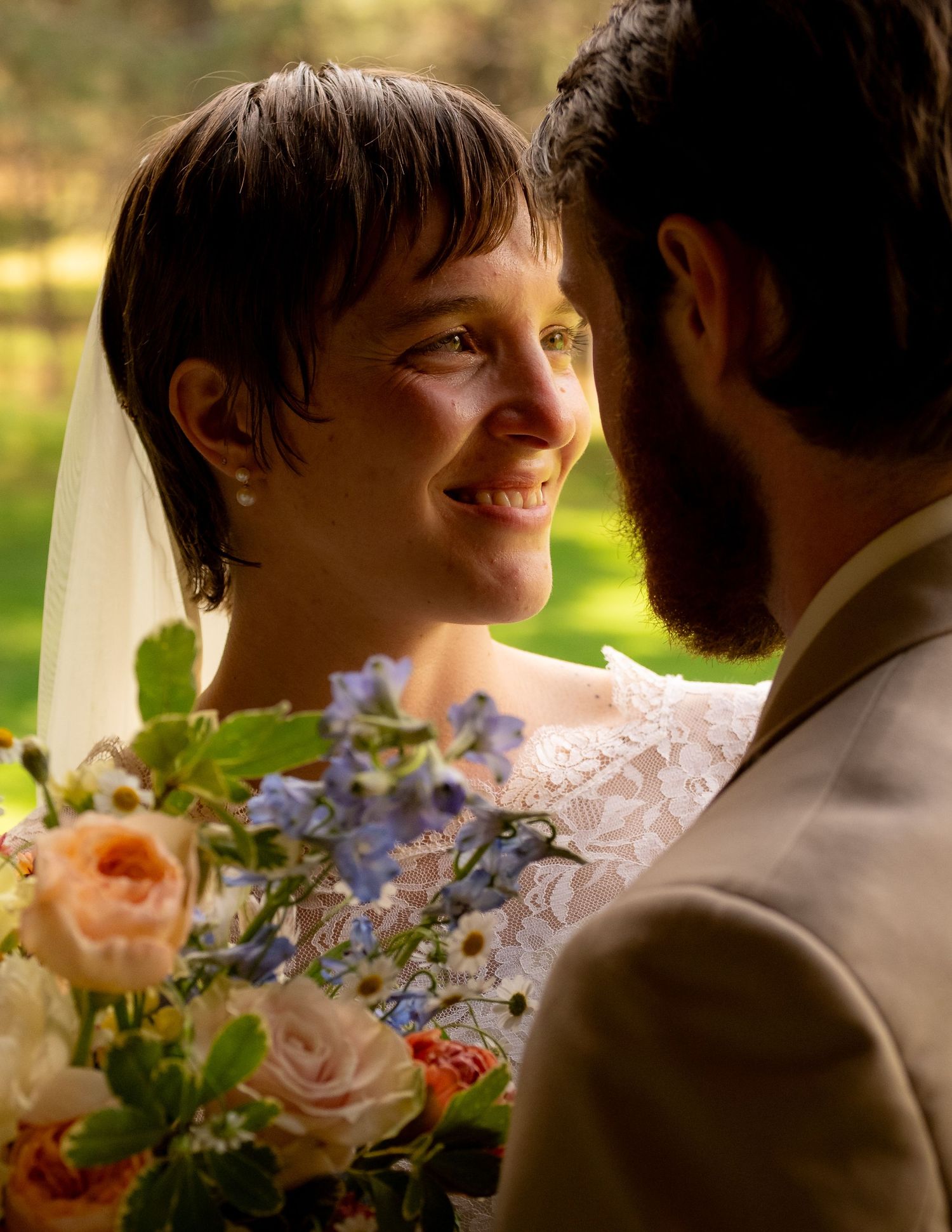 A tender moment captured during an outdoor wedding with colorful floral bouquet details.