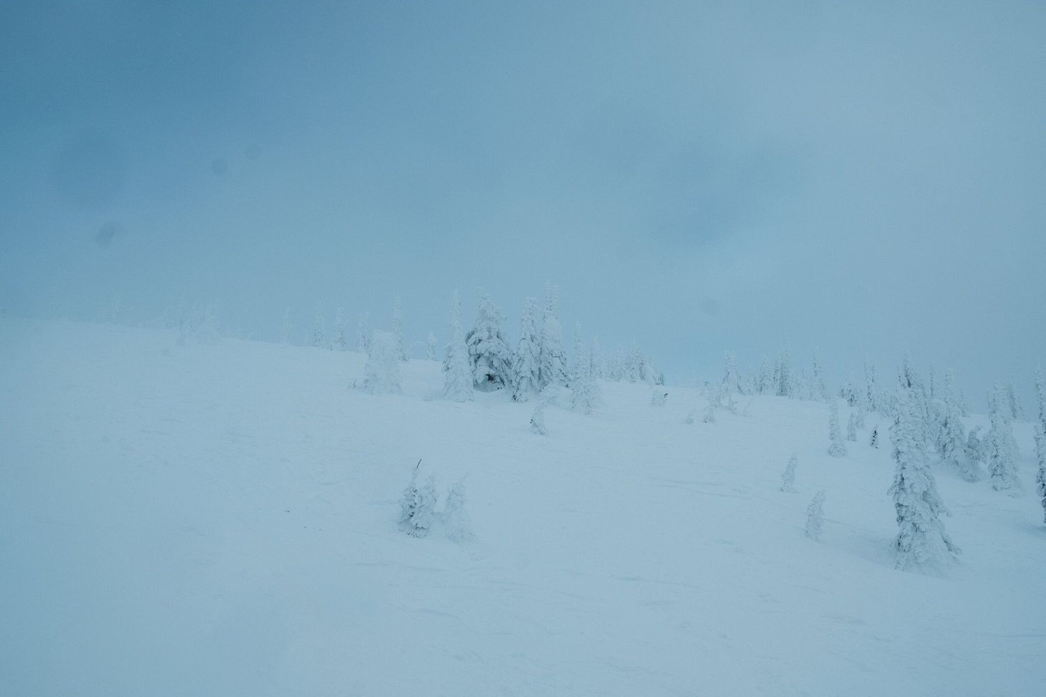Snowy mountain landscape panorama with misty clouds and white winter terrain.