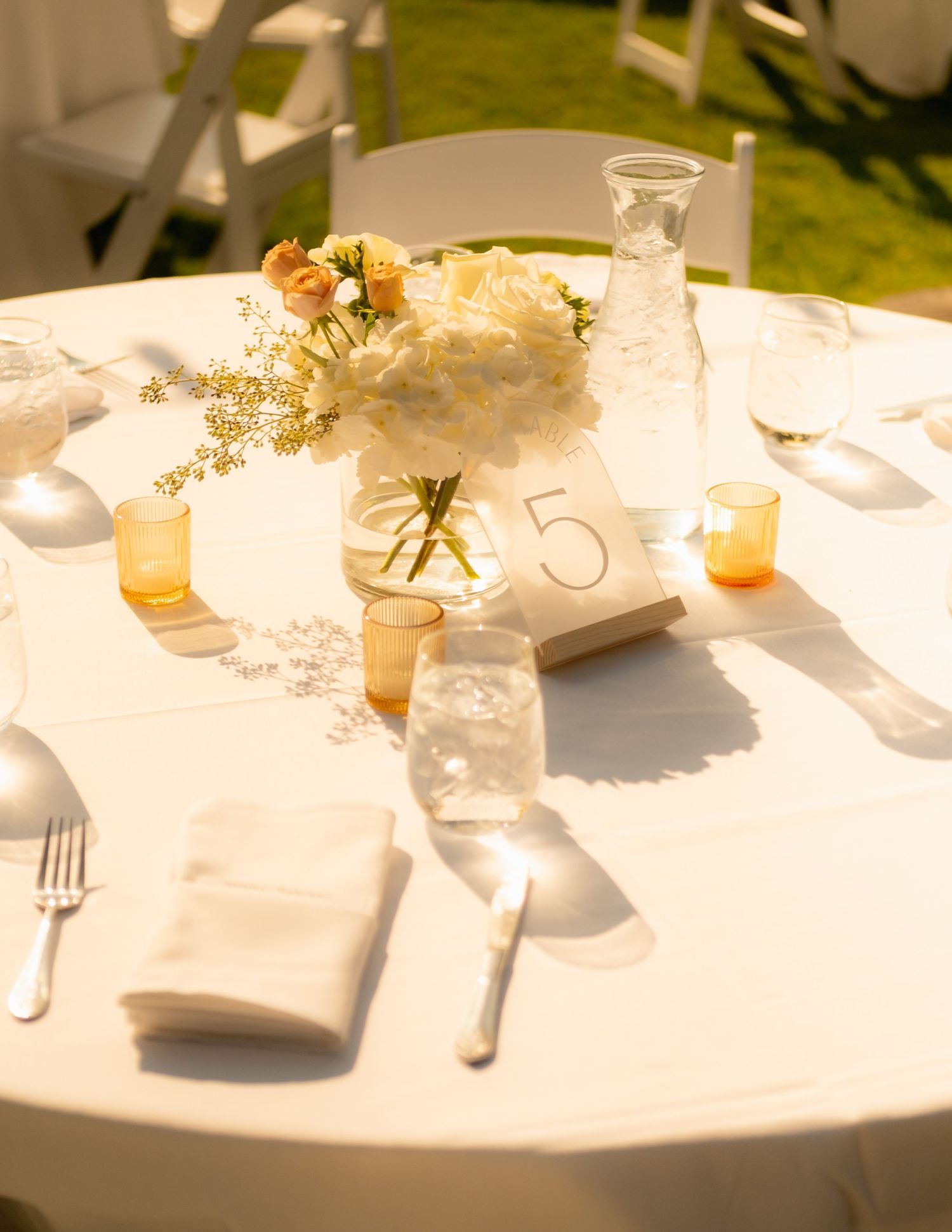 Elegant wedding table setting with floral centerpiece and glasses in natural light.