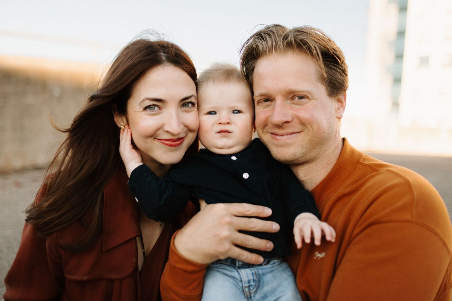 A loving family poses together outdoors in warm autumn colors during a lifestyle photo session.