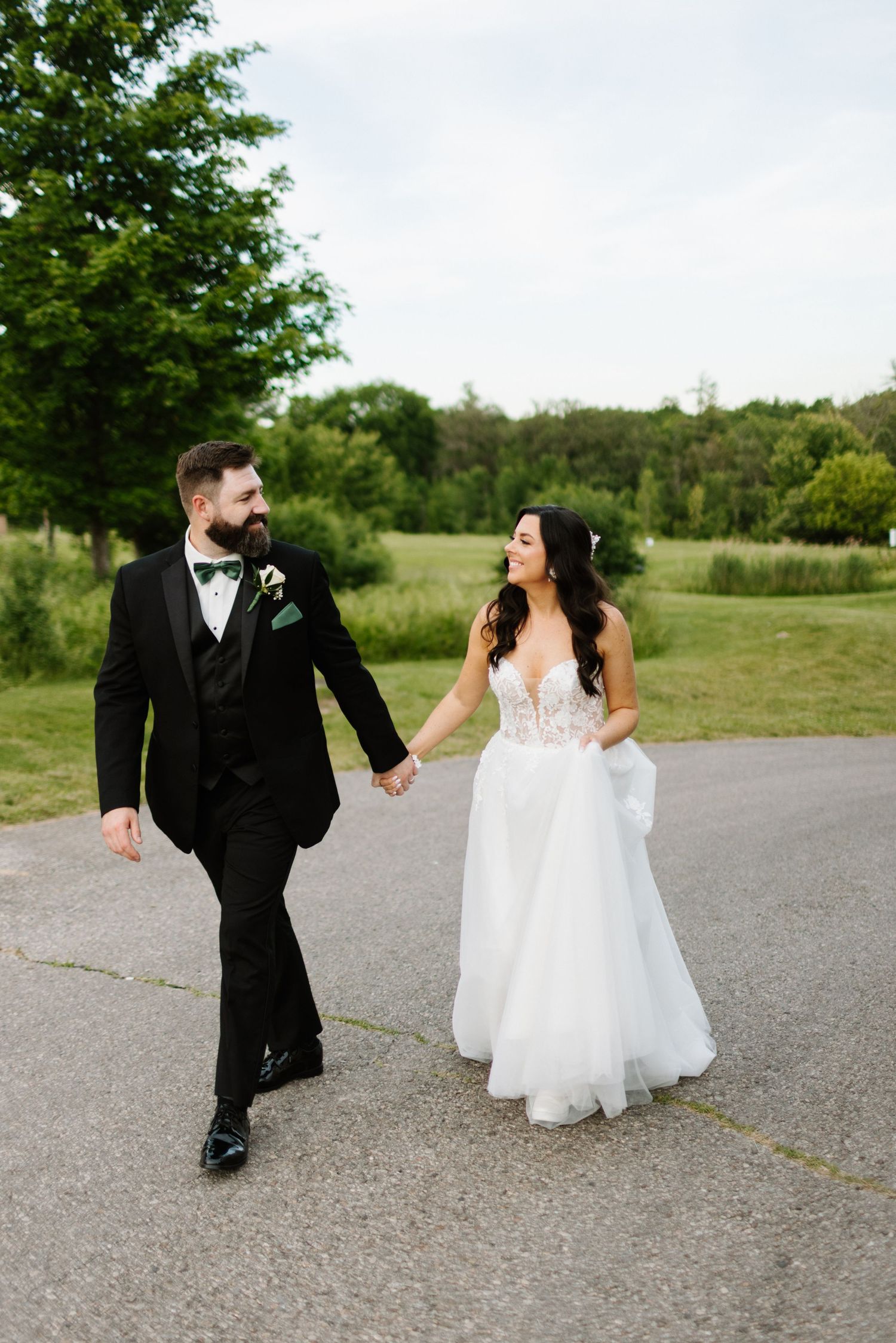 A couple in wedding attire walking and holding hands on Grey Silo golf course in Kitchener Ontario