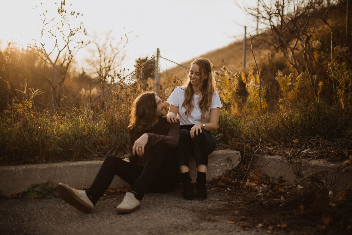 Couple sharing an intimate moment while sitting on outdoor steps at sunset.