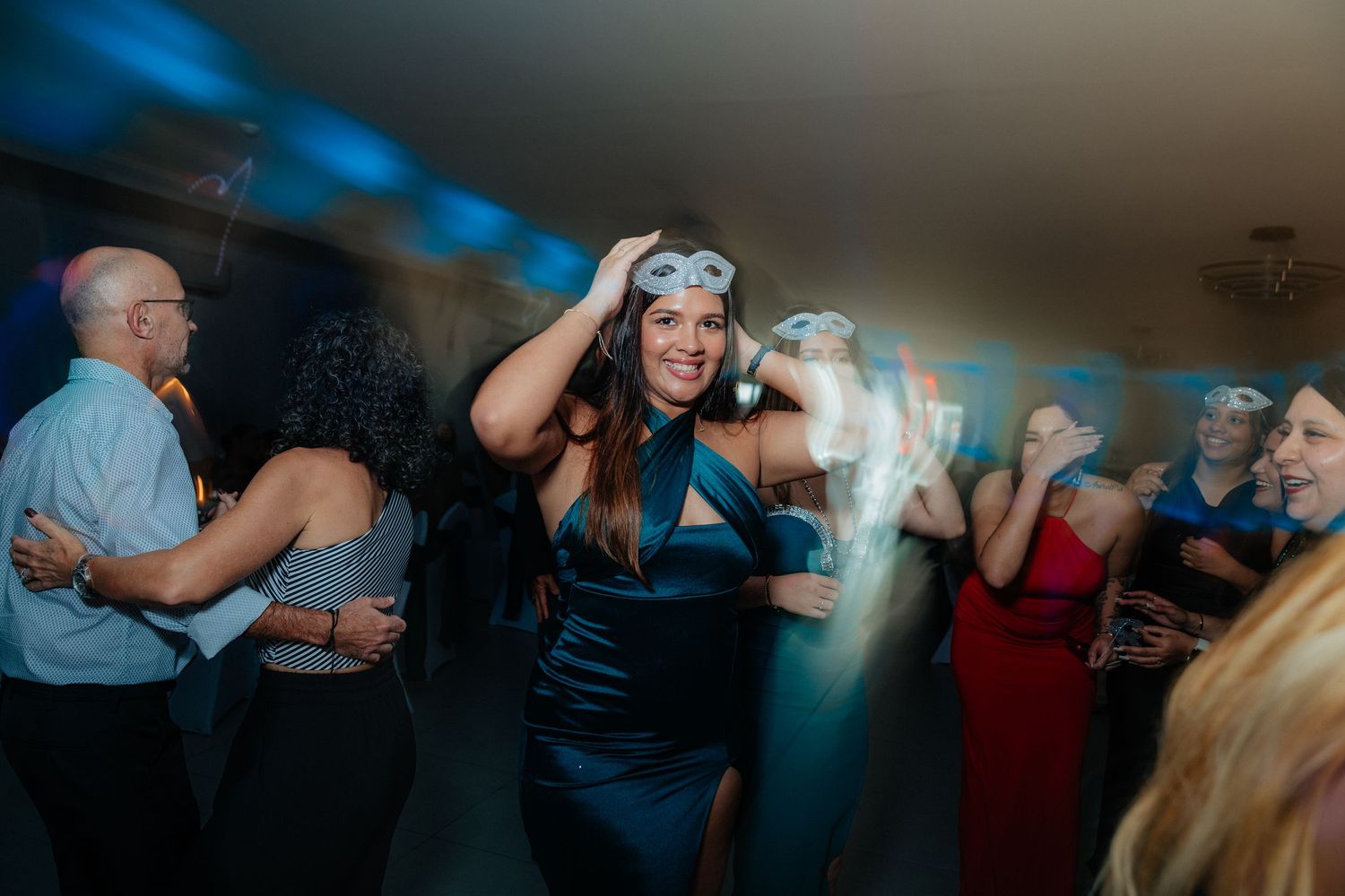 Lively dance party scene with guests moving under atmospheric blue lighting.