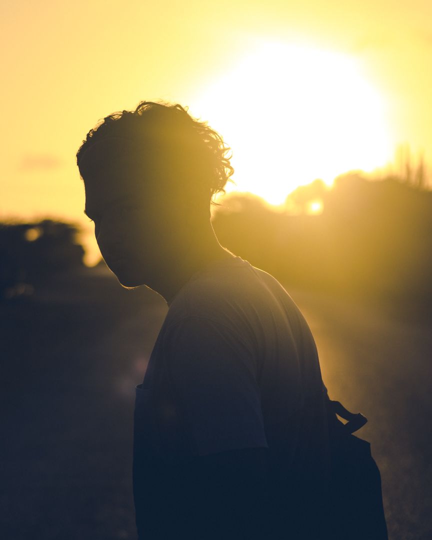 Silhouettes against golden sunset sky creating dramatic backlit portrait.