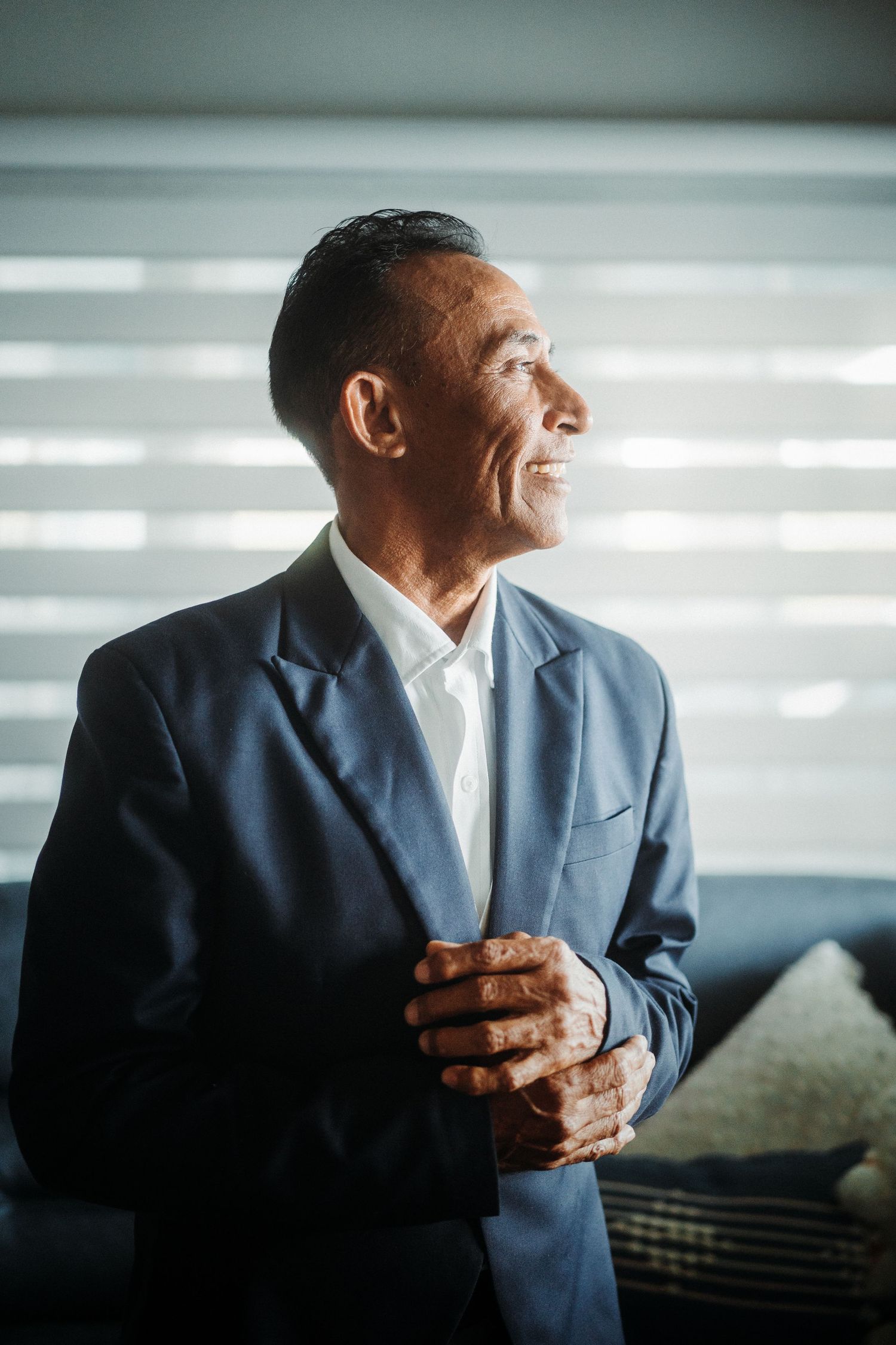 Professional in blue suit looking to side with clasped hands.