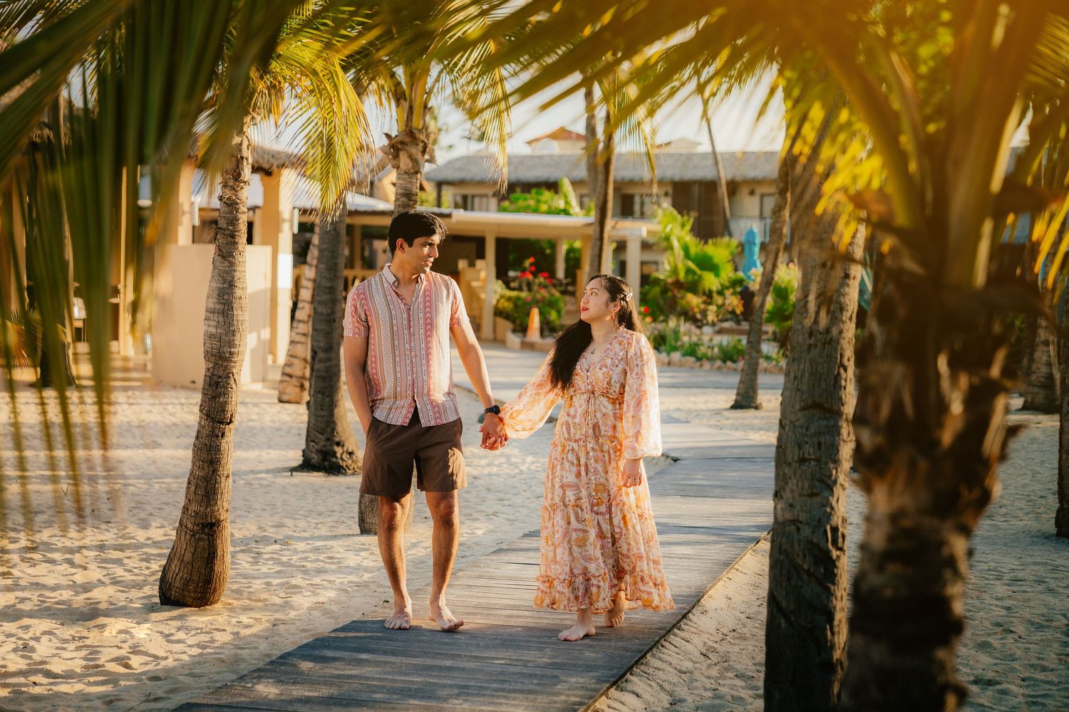 Romantic sunset beach photo session with palm trees creating a dreamy silhouette effect.