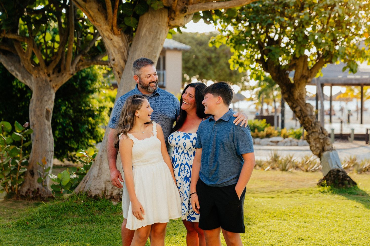 Group enjoying a sunny moment together on lush green lawn with tropical trees in background.