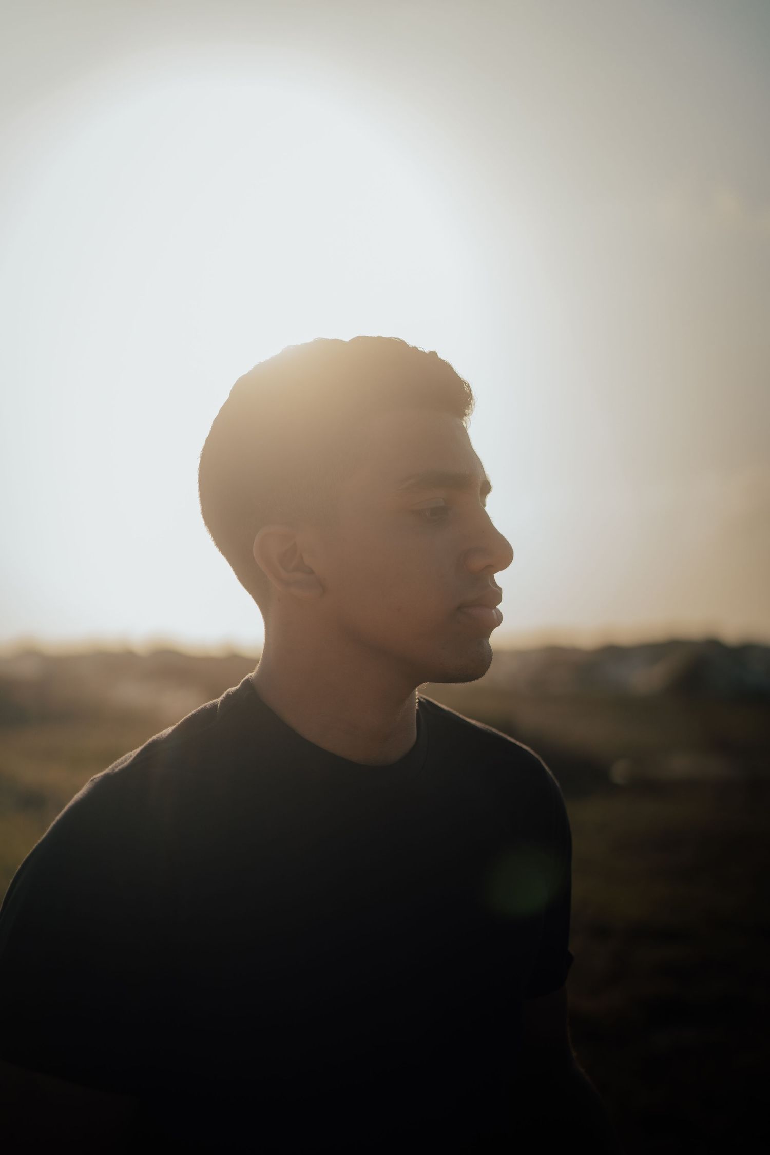 Profile silhouette against bright sky in dramatic lighting.