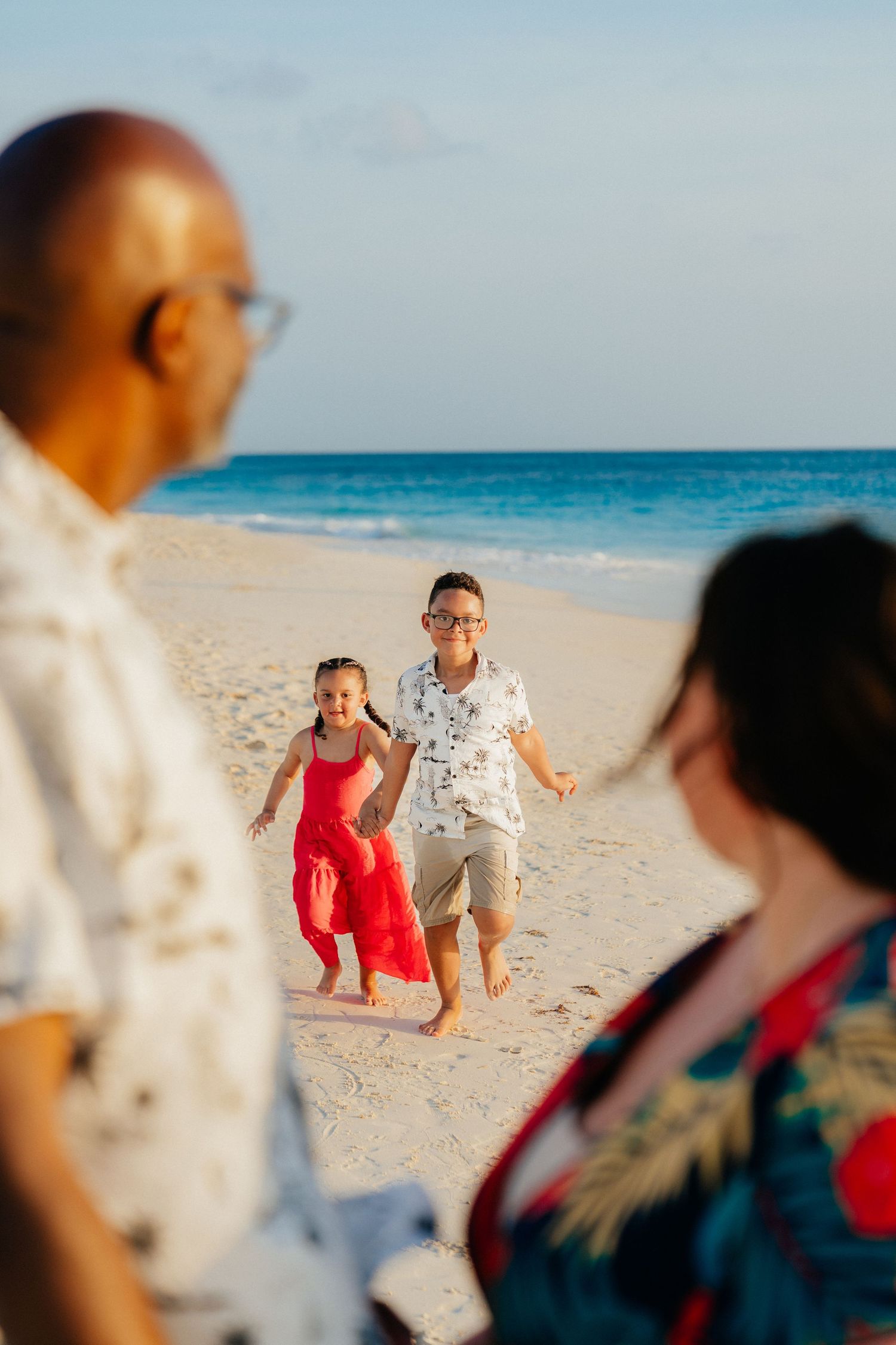 Candid beach photography session with people playing and running on the sand.