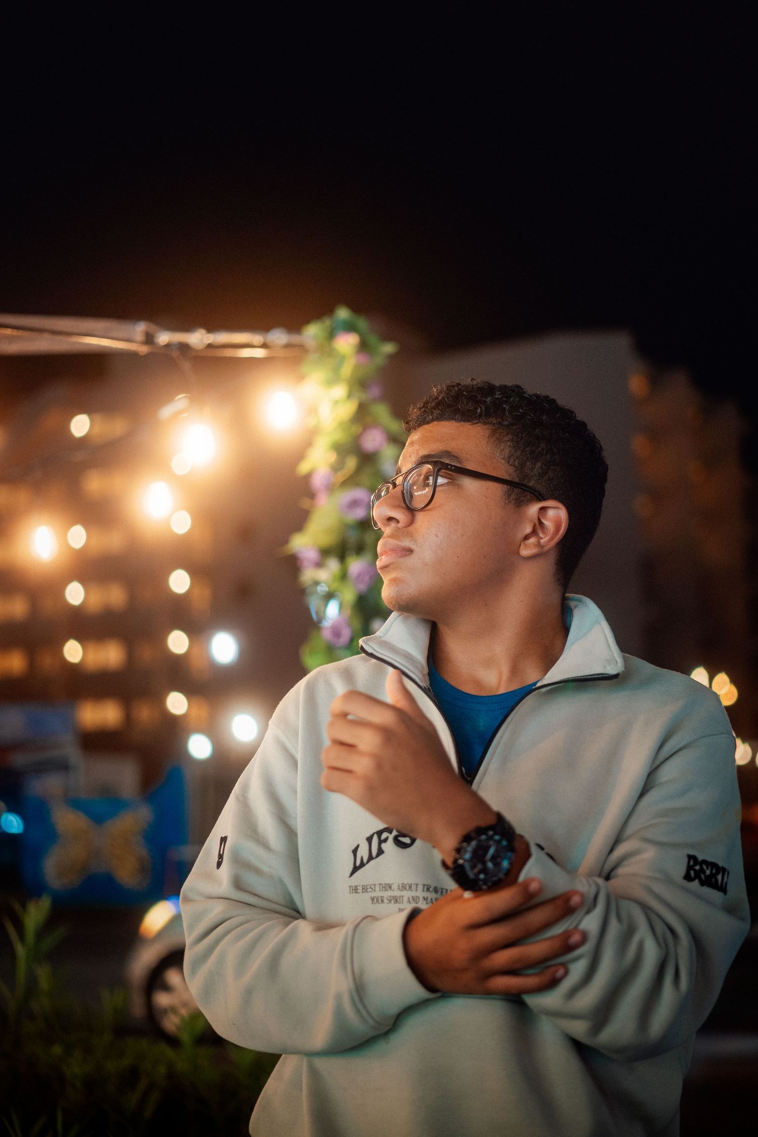 Person in white hoodie under string lights at night.