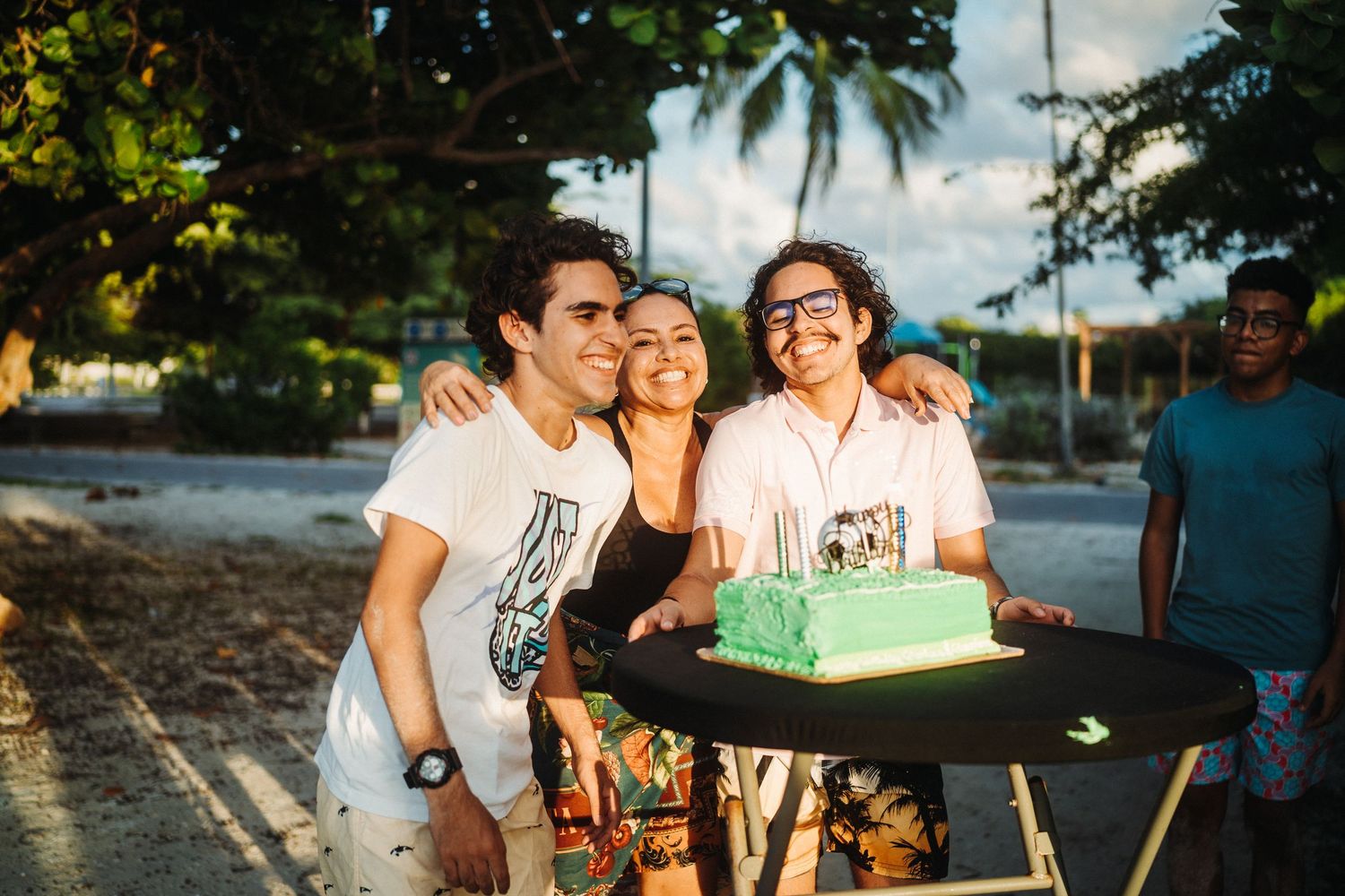 Friends enjoying outdoor party with cake and decorations at dusk.