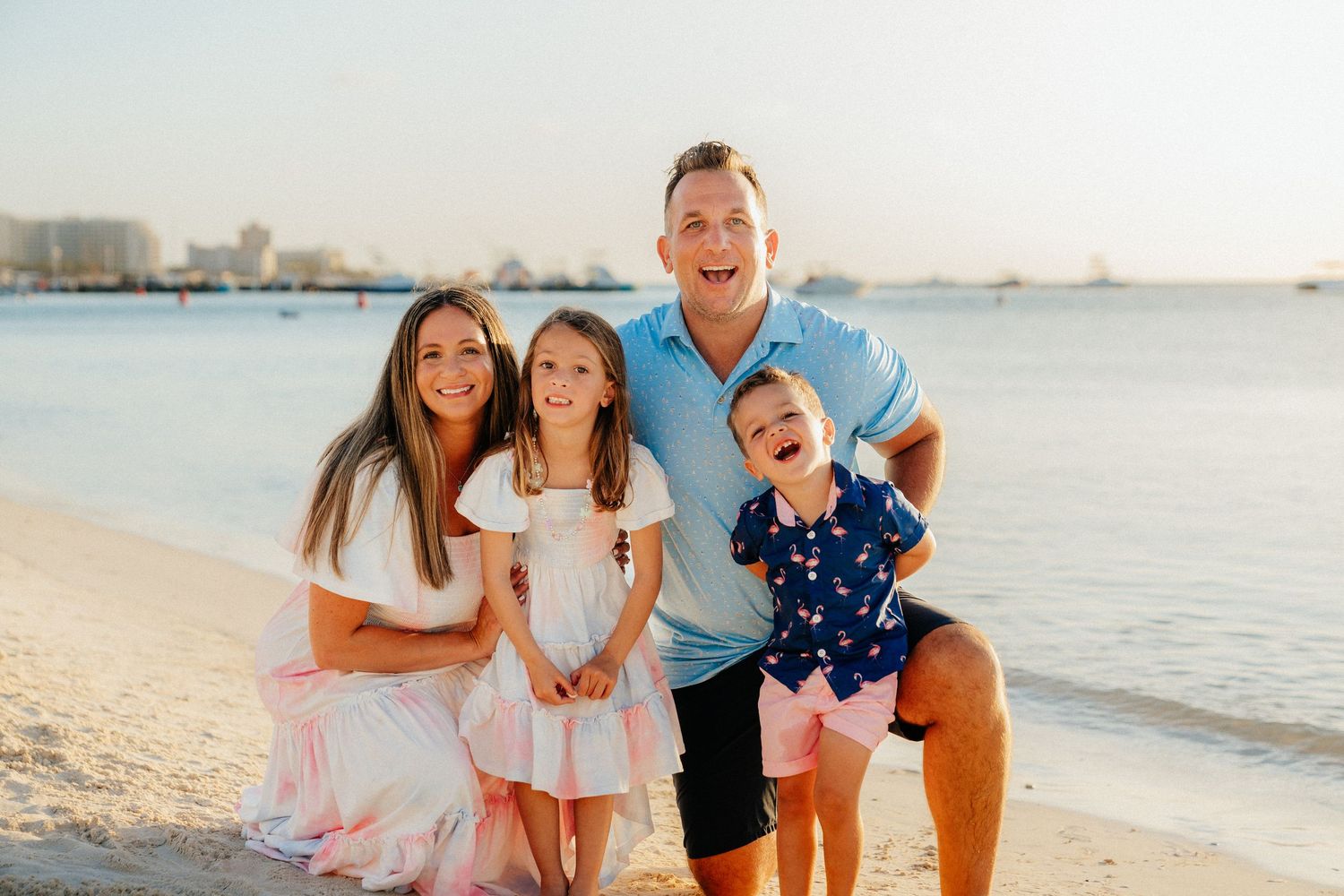 Family enjoying a sunny day at the beach with waves and sand in the background.