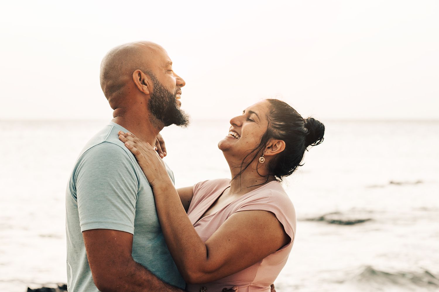 Couple sharing intimate moments on a sandy beach at sunset.