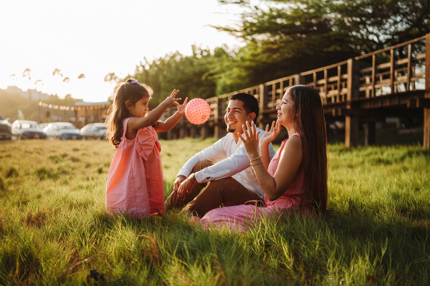 Family members relax together in a grassy field during golden hour.