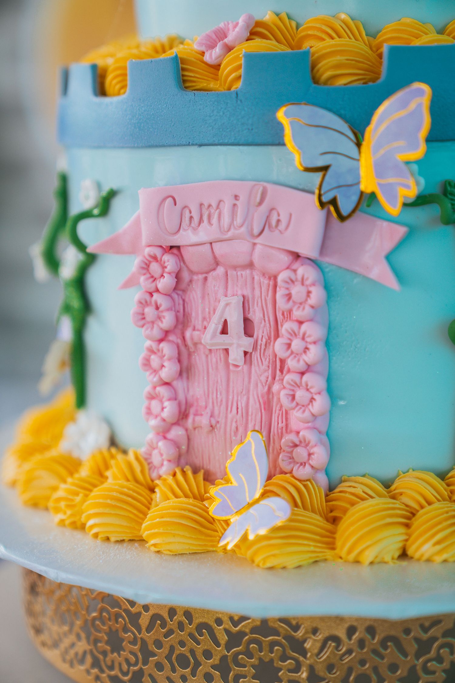 Close-up of an elegant pink and yellow birthday cake with decorative floral details.
