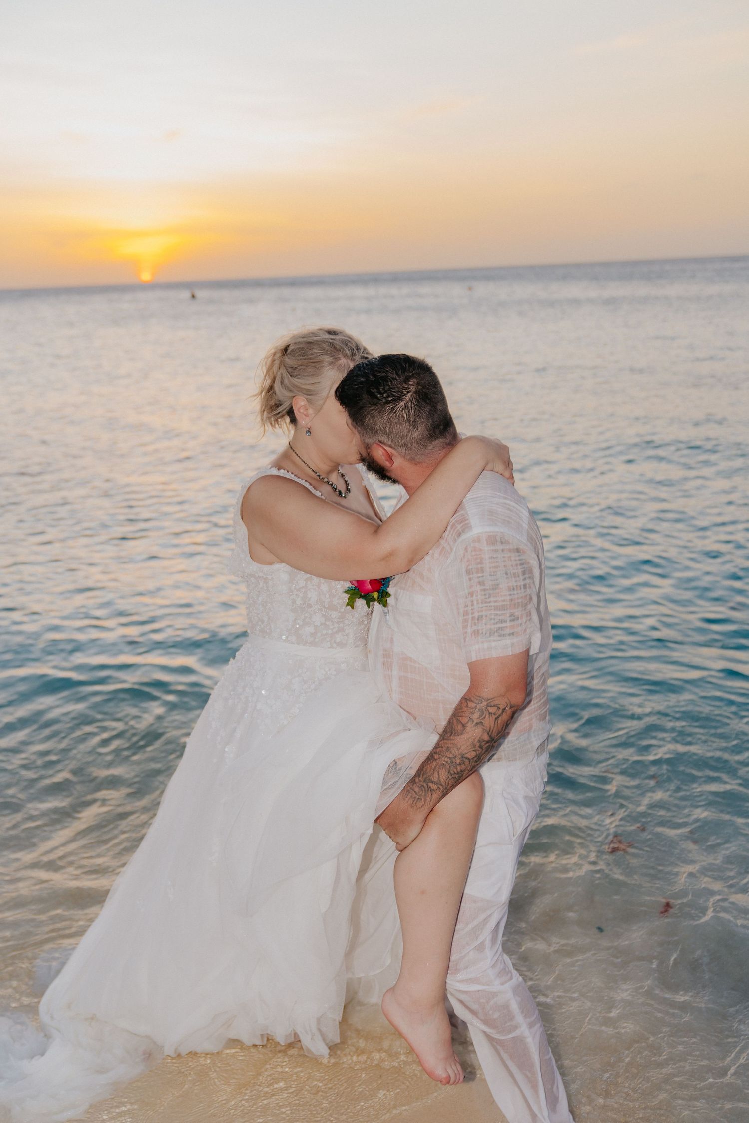 Romantic sunset moment between newlyweds at the water's edge.