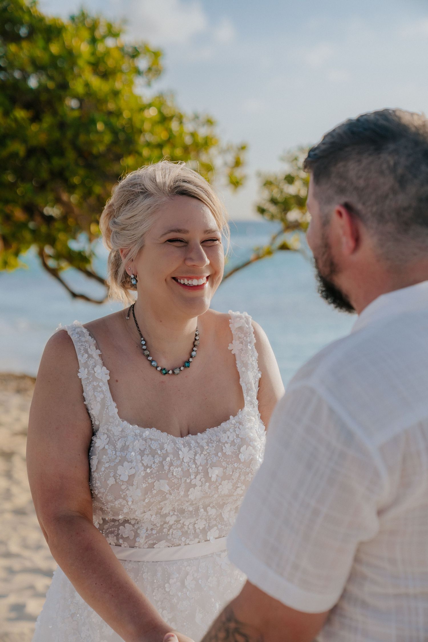 A joyful moment during a beachside wedding ceremony with the ocean in the background.