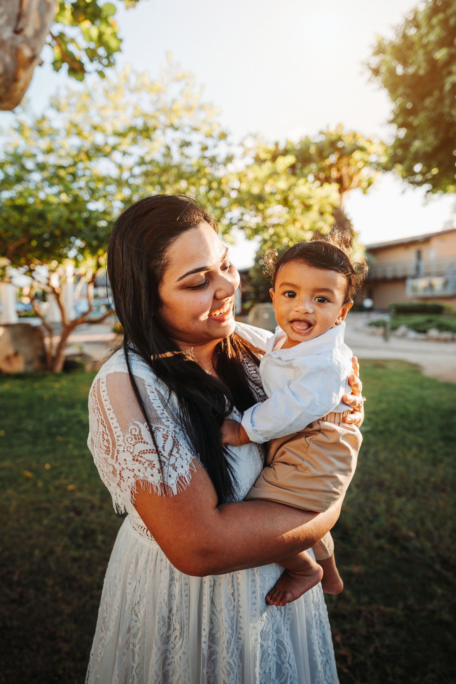 Sweet moments captured between parent and child in white lace dress outdoors.