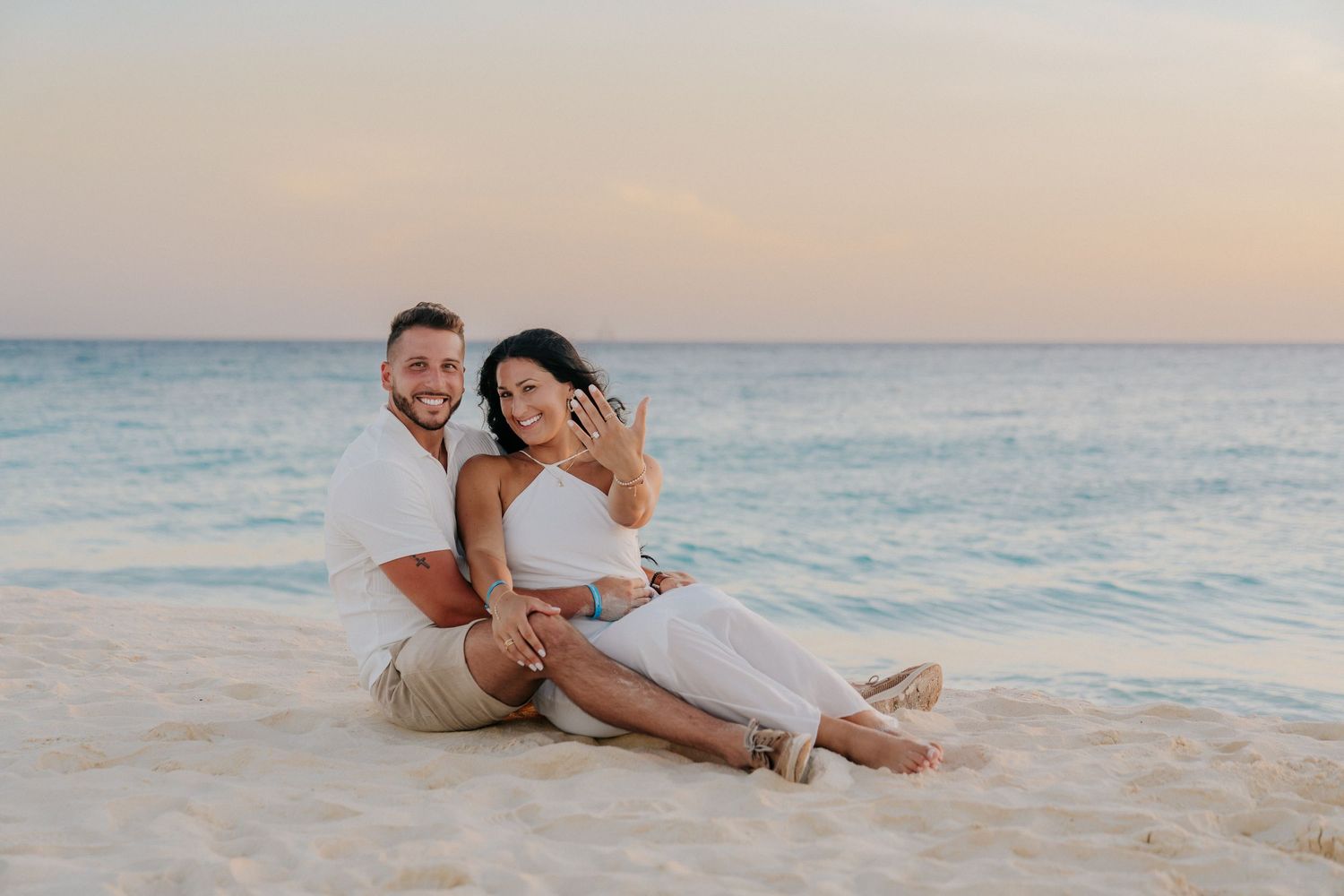 A couple shares romantic moments on a sandy beach during golden hour.