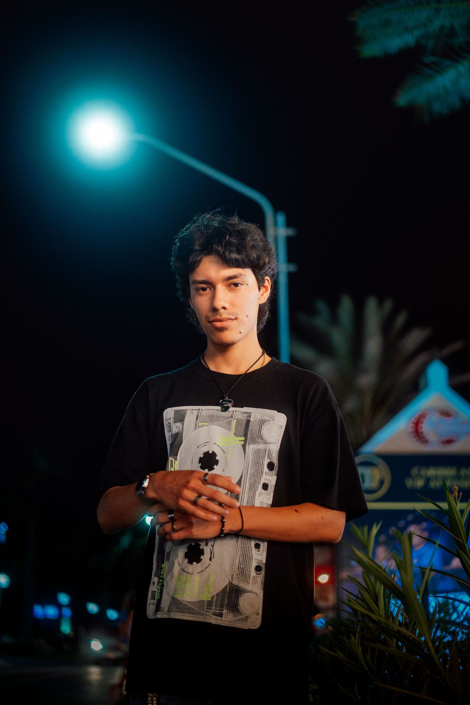 Person in graphic t-shirt standing under blue night lighting.